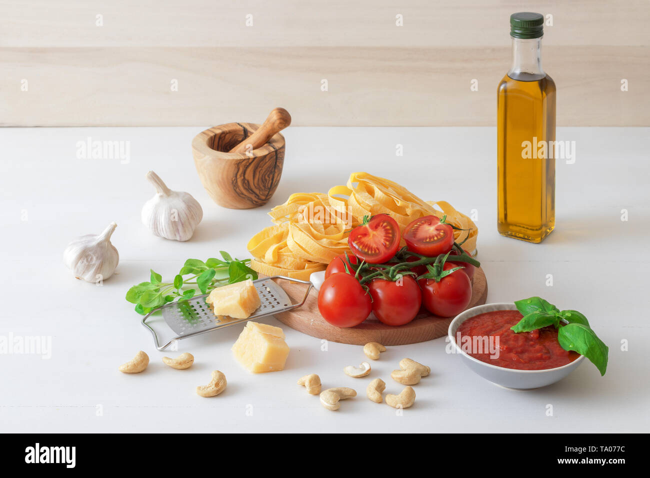 Tabelle mit Zutaten Tomaten pesto machen. Tomaten, Knoblauch, frischer Oregano und Basilikum Kräuter, eine Flasche Olivenöl, paar Cashewnüsse, Parmesan, c Stockfoto