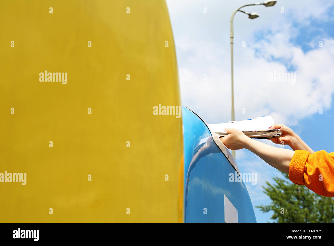 Recycling, eine Frau wirft Papier Abfall in einen blauen Container Stockfoto