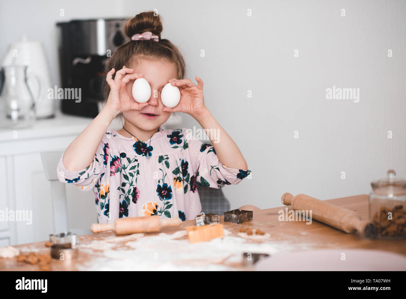 Lächelnd kind Mädchen 4-5 Jahre alten Spaß mit rohen Eiern in der Küche. Die cookies im Innenbereich. Kindheit. Stockfoto