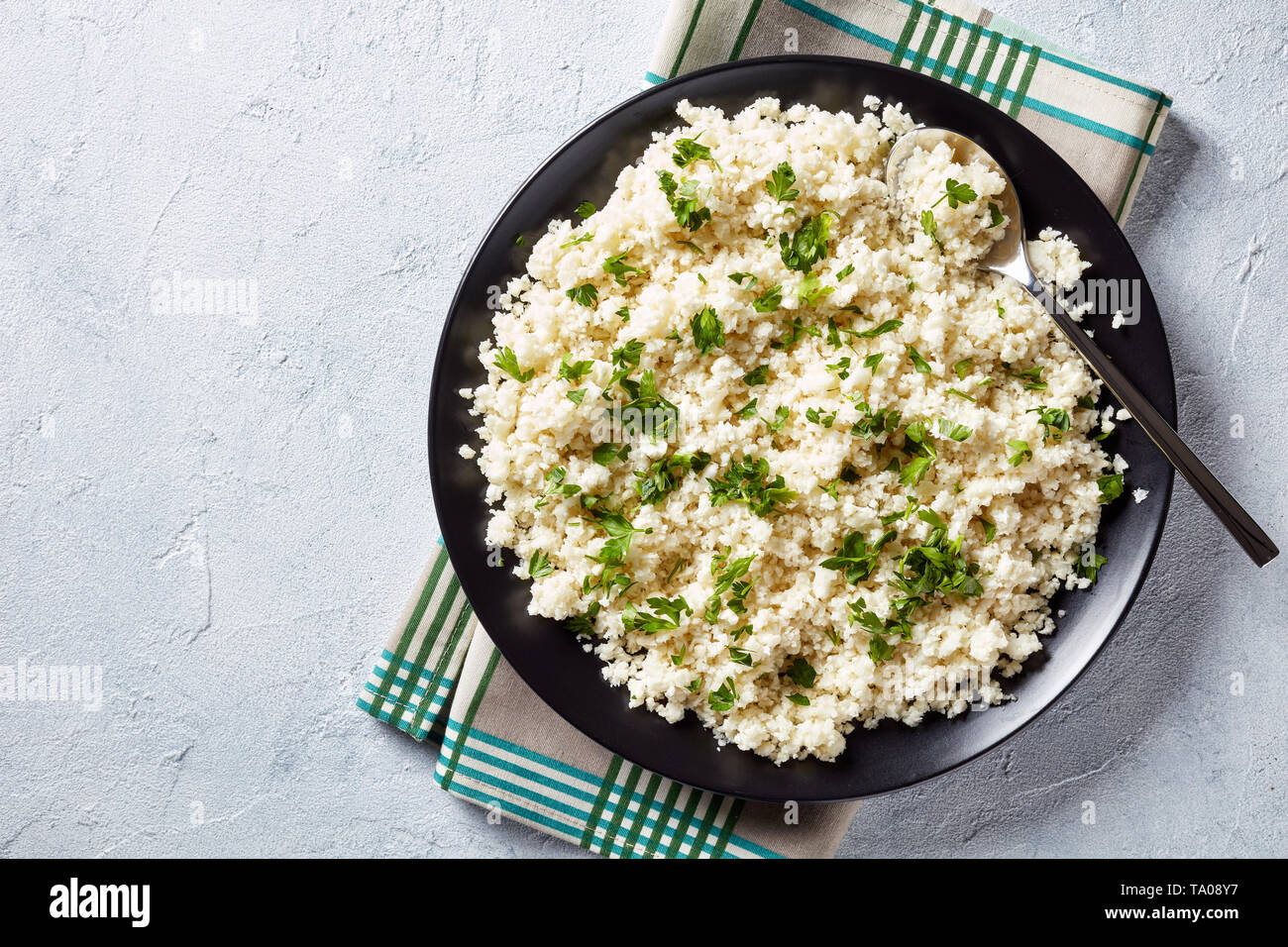 Blumenkohl, Reis oder Couscous mit gehackter Petersilie in einer Schüssel auf einem weißen Tisch Beton gemischt, gesunde Ernährung, wenig Kalorien essen, Schmierfilm Stockfoto