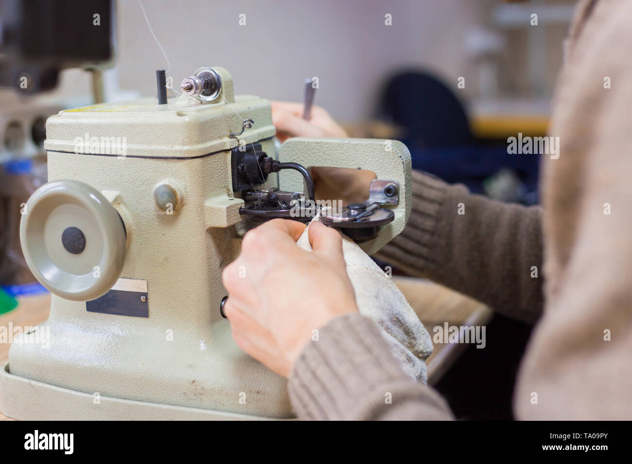 Professionelle männlichen Skinner, Kürschner mit speziellen Nähmaschine für das Zusammenfügen von Fell Haut im Atelier, Werkstatt. Mode- und Lederarbeiten Konzept Stockfoto