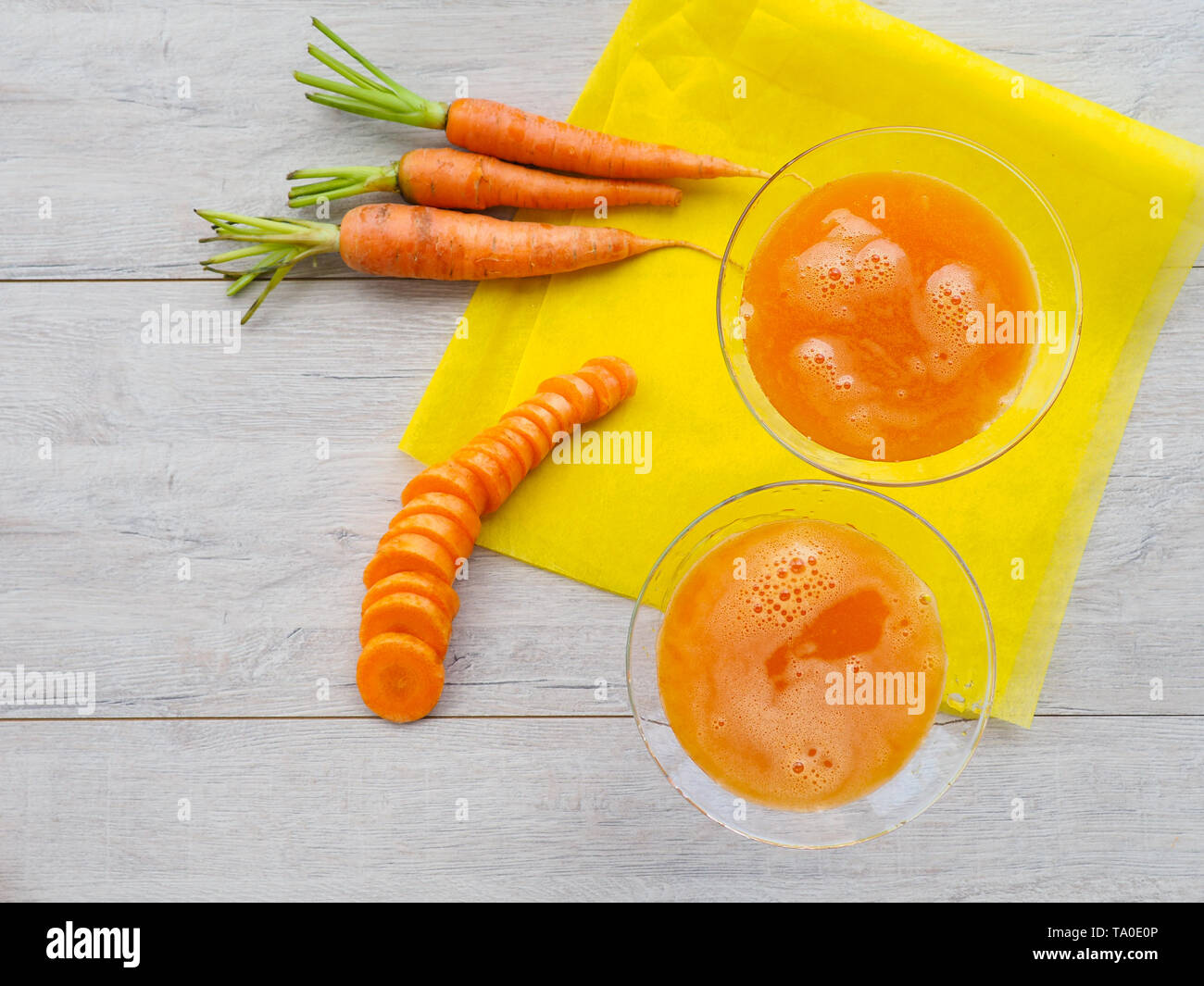 Gläser Karottensaft und frische Karotten auf Holzbrett Stockfoto