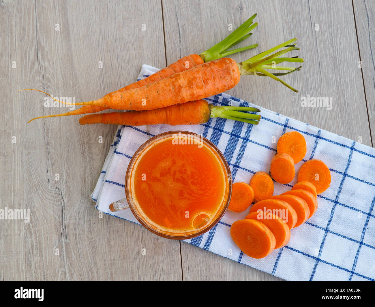 Gläser Karottensaft und frische Karotten auf Holzbrett Stockfoto