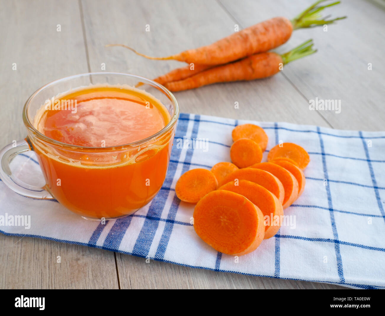 Gläser Karottensaft und frische Karotten auf Holzbrett Stockfoto
