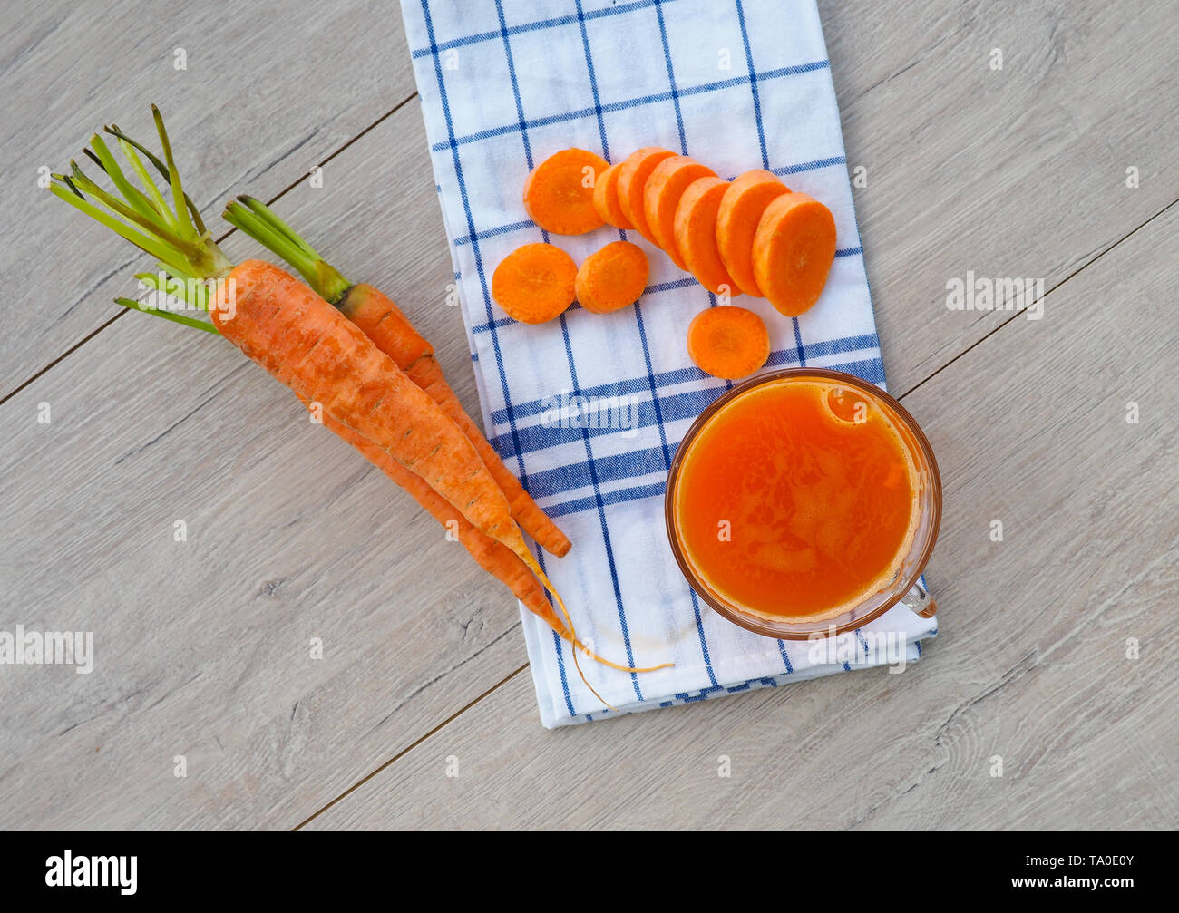 Gläser Karottensaft und frische Karotten auf Holzbrett Stockfoto