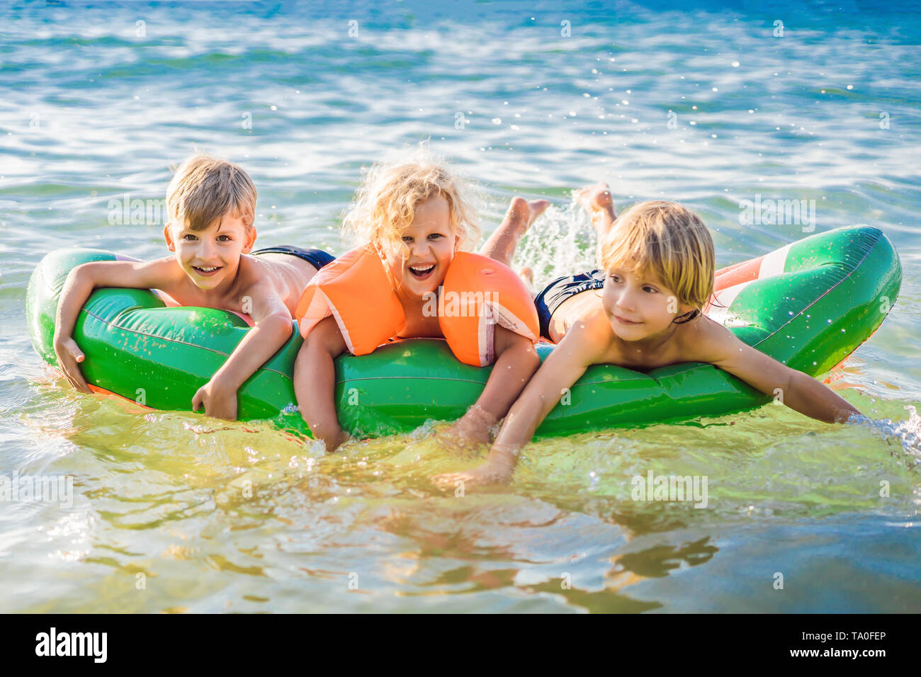 Kinder schwimmen im Meer auf einer aufblasbaren Matratze und Spaß haben Stockfoto