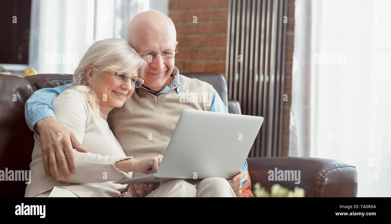 Senior Paar gemeinsam im Internet surfen. Rentner mit einem Laptop Computer zu Hause. Web Banner Bild Hintergrund mit Kopie Raum Stockfoto