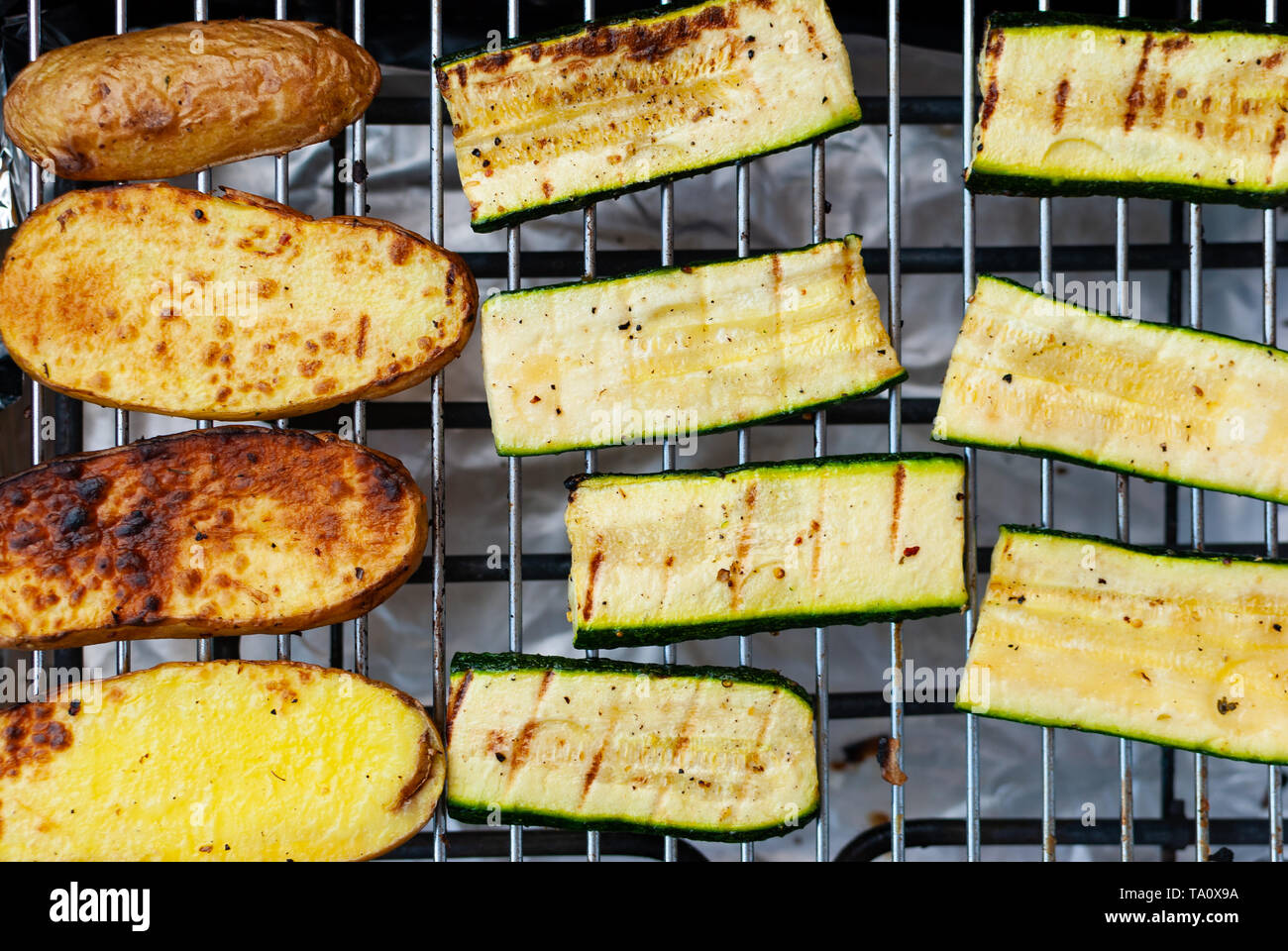 Nahaufnahme von gegrilltem Gemüse auf dem Braten - Kartoffeln und Zucchini - vegan Stockfoto