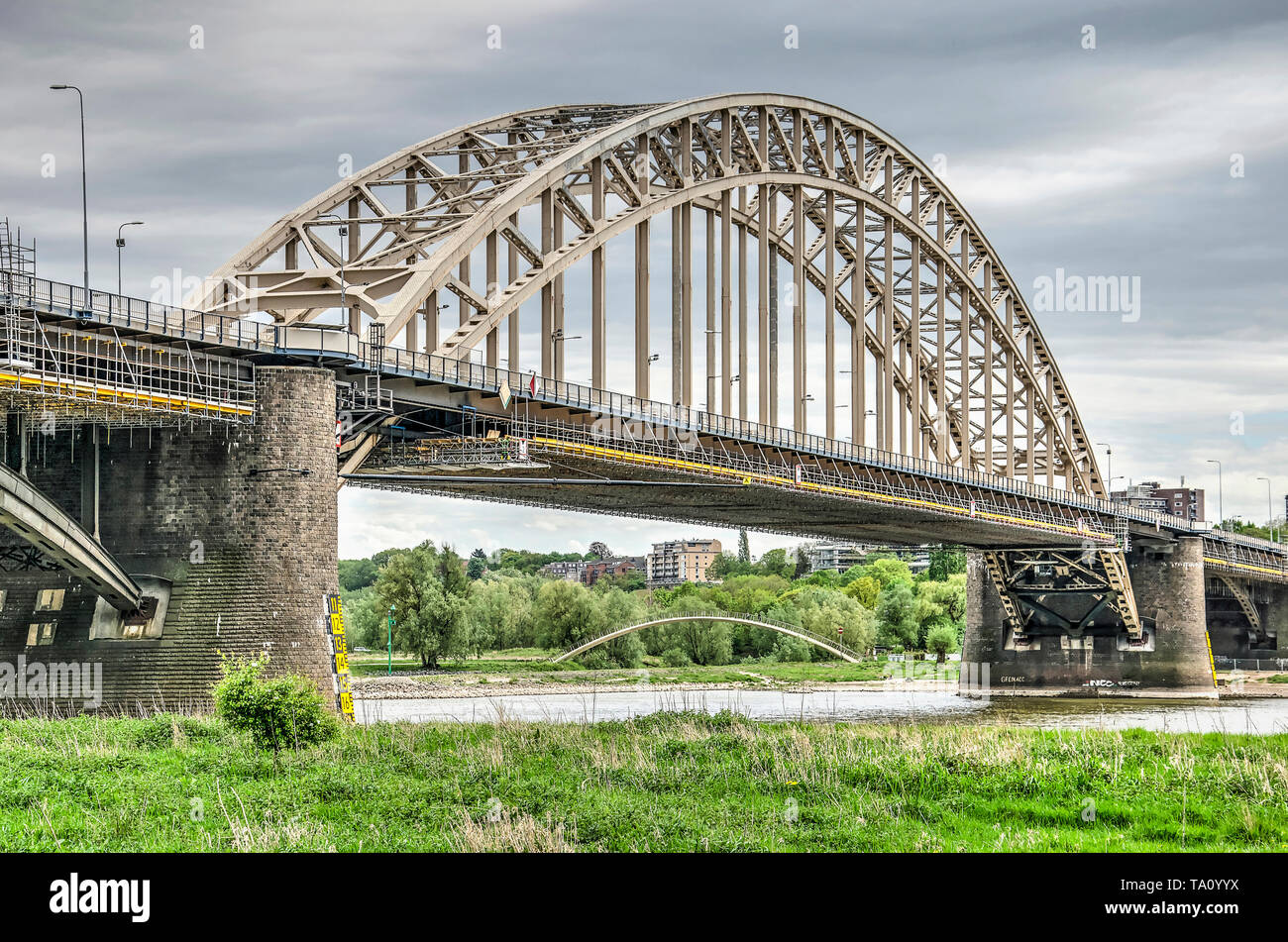 Nijmegen, Niederlande, April 25, 2019: Der alte Stahl Bogen Brücke über den Fluss Waal, der Reparatur, der mit unten, im Hintergrund, moderne pedestria Stockfoto