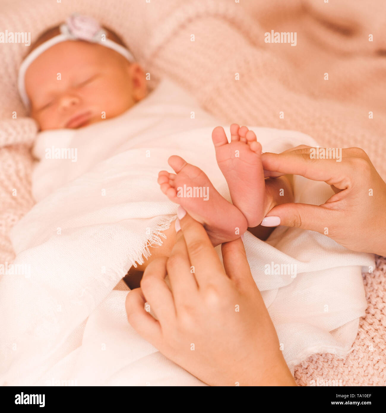 Mutter Holding baby Füße im Bett Nahaufnahme. Die Mutterschaft. Mutterschaft. Stockfoto