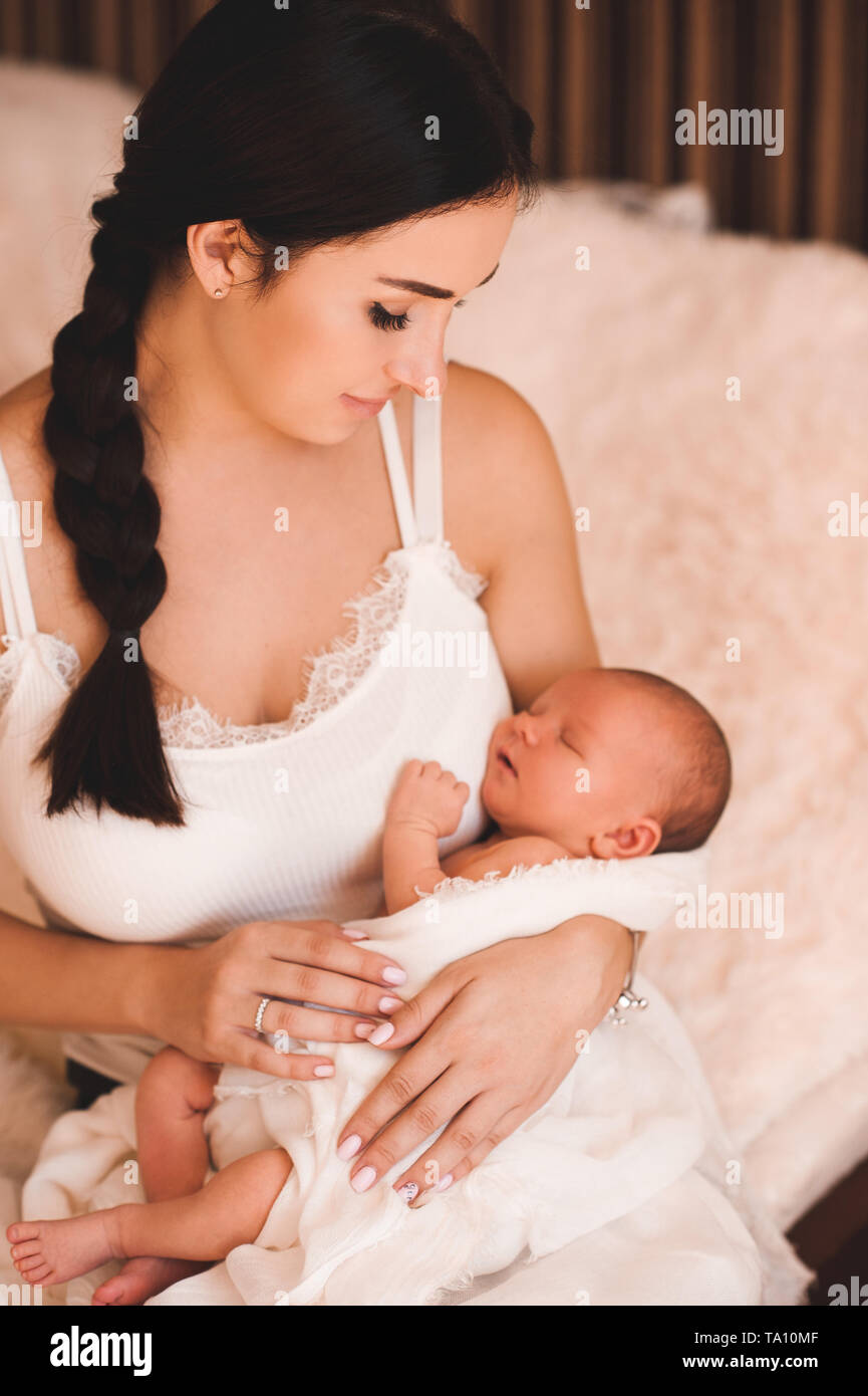 Lächelnde Mutter Holding schlafendes Baby im Bett sitzen Nahaufnahme. Mutterschaft. Die Mutterschaft. Stockfoto