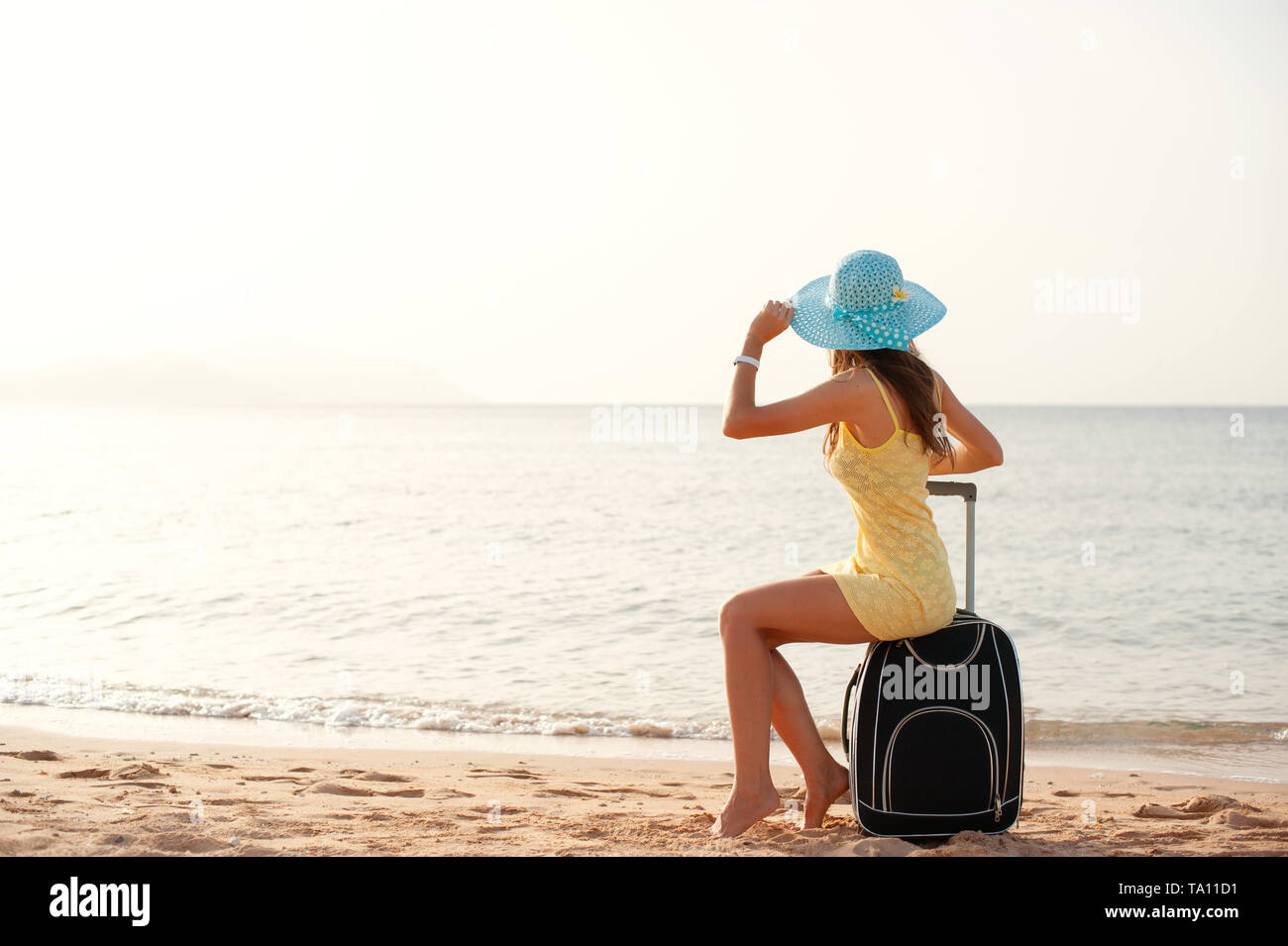 Reisen Urlaub und Personen Konzept - Frau Tourist in der Nähe von dem Meer sitzen auf Koffer und in Hut und beobachten die Sonne und alle Daumen hoch Stockfoto Reisen Urlaub und Personen Konzept - Frau Tourist in der Nähe von dem Meer sitzen auf Koffer und in Hut und beobachten die Sonne und alle Daumen hoch Stockfoto