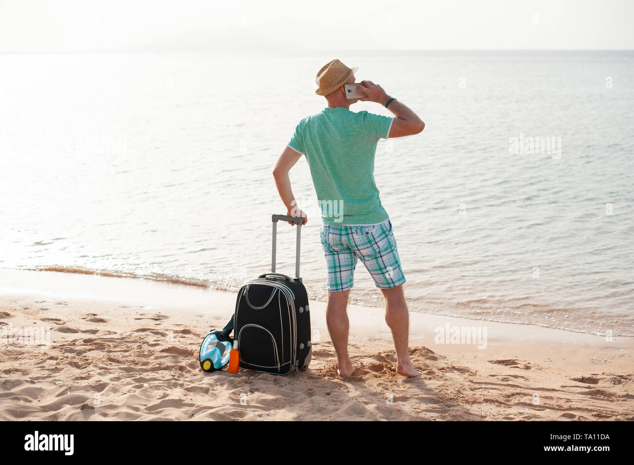 Natur reisen Personen Konzept - Mann stand in der Nähe vom Meer am Strand mit Koffer und sprechen über das Telefon Stockfoto Natur reisen Personen Konzept - Mann stand in der Nähe vom Meer am Strand mit Koffer und sprechen über das Telefon Stockfoto