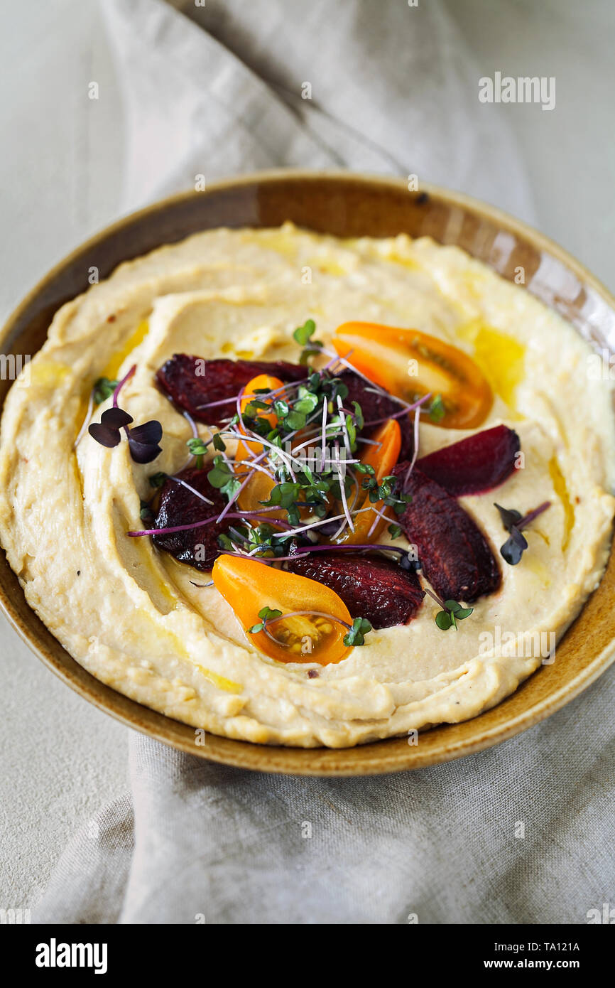 Traditionelle klassische mediterrane hummus Kichererbsen mit Olivenöl mit Cherry Tomaten, geröstete Rüben und Micro Grüns serviert. Gesund und nutritiou Stockfoto