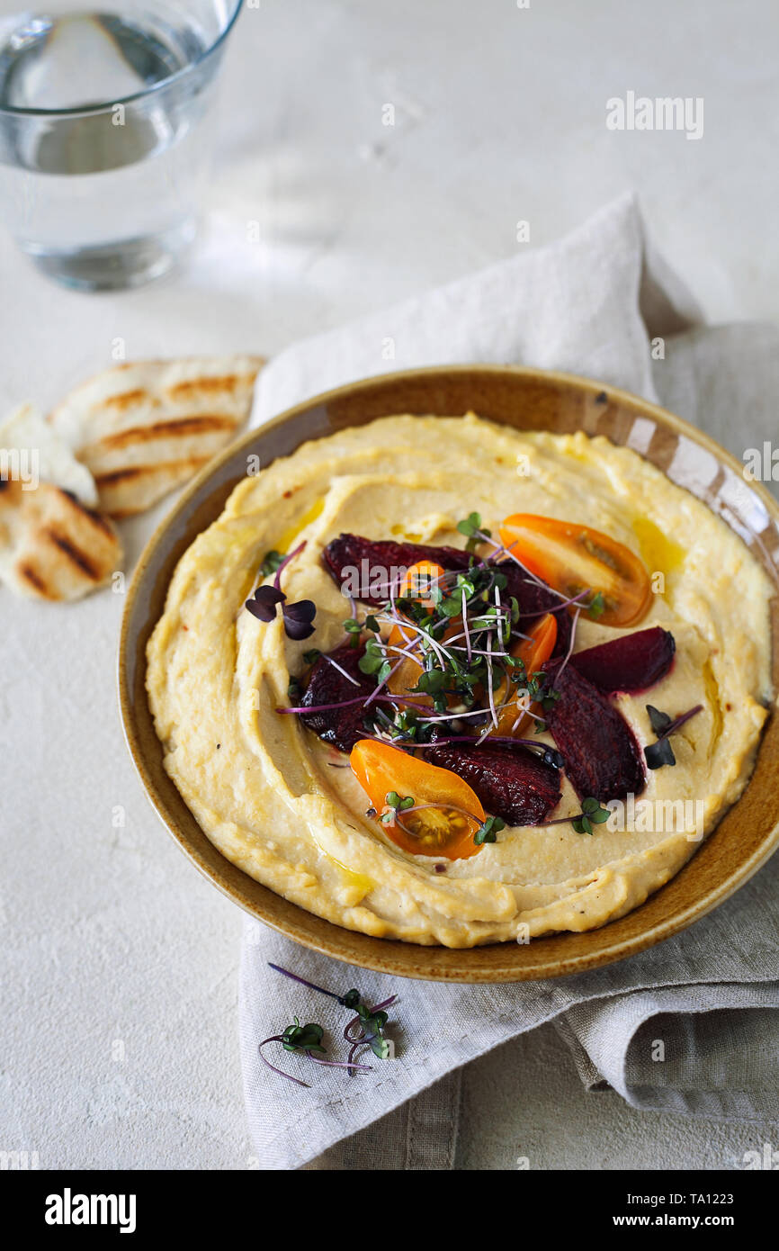 Traditionelle klassische mediterrane hummus Kichererbsen mit Olivenöl mit Cherry Tomaten, geröstete Rüben und Micro Grüns serviert. Gesund und nutritiou Stockfoto