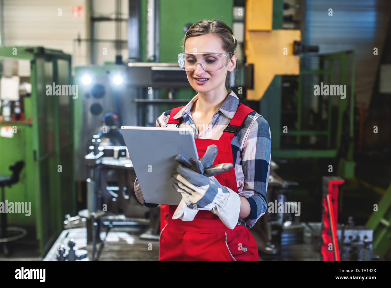 Arbeiterin mit Tablet-PC in der Vorderseite der Maschine Stockfoto