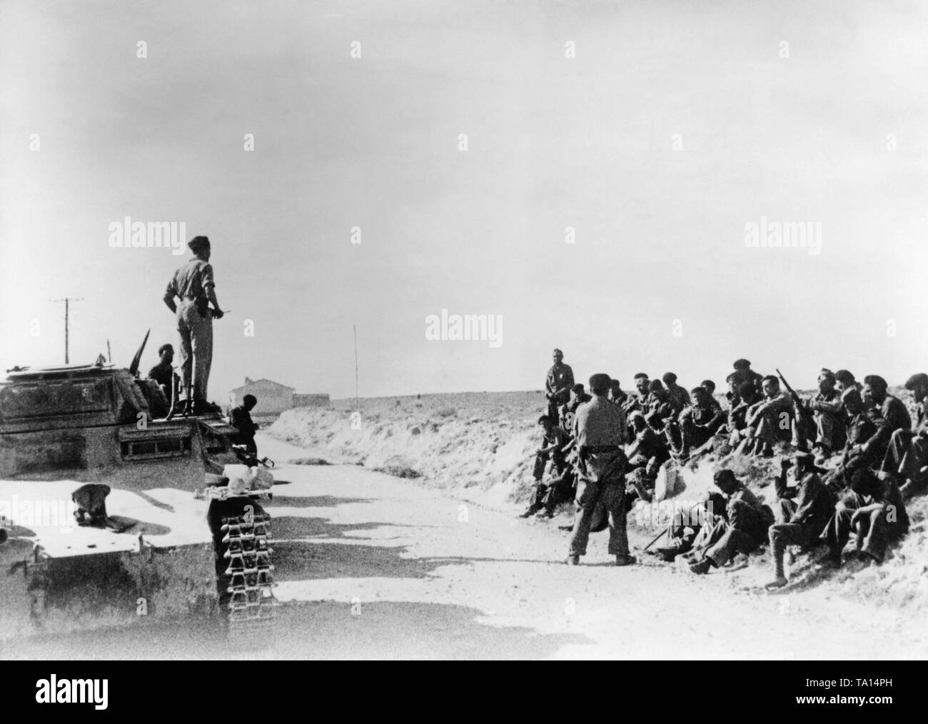 Foto eines Offiziers (auf der linken Seite, wahrscheinlich ein deutscher Panzer Commander) Adressierung an die Soldaten (rechts, sitzend auf den Straßenrand) Der spanische nationale Fraktion in 1938. Der Offizier steht auf einem deutschen Panzer, ein panzerkampfwagen (Armored Fighting Vehicle) I (PzKpfw I). Stockfoto