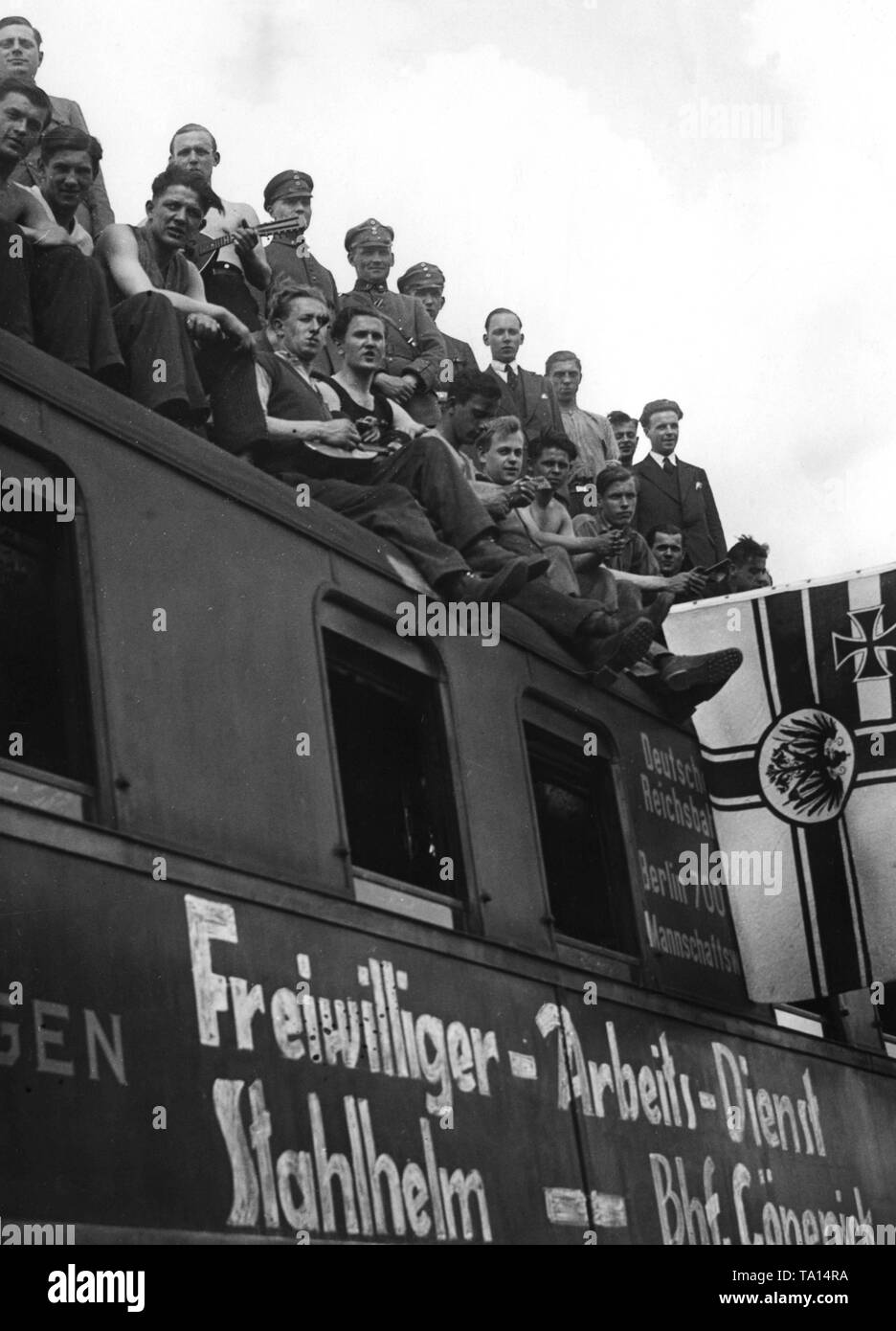 Blick auf eine Gruppe von Freiwilligen der Stahlhelm auf einem mannschaftswagen der Deutschen Reichsbahn (Deutschen) mit einem Schlaf und eine Küche, die auf der Berliner Güterbahnhof Köpenick geparkt ist. Auf der rechten Seite, der ehemaligen kaiserlichen Krieg Flagge des Deutschen Reiches. Stockfoto