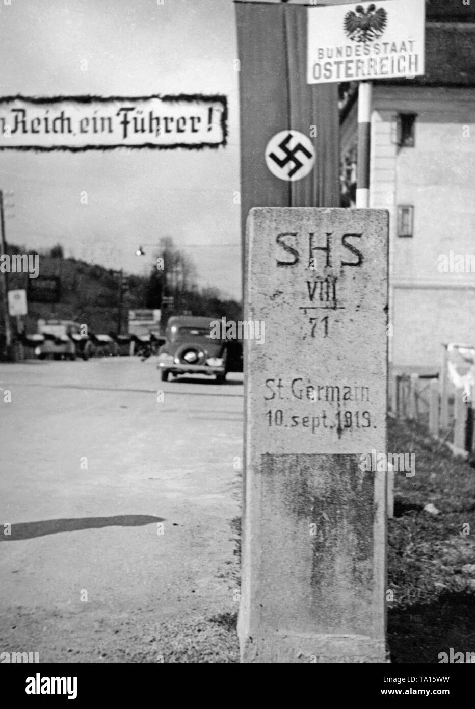 Gedenkstein für den Vertrag von Saint Germain, der erklärte, dass die österreichisch-ungarischen Monarchie wurde nach dem Ersten Weltkrieg aufgelöst werden zu können. Der Stein steht an der deutsch-österreichischen Grenze. Im Hintergrund ein Plakat: "Ein Reich, ein Führer". Mit der Annexion Österreichs an das Deutsche Reich wurde der Vertrag unwirksam. Stockfoto
