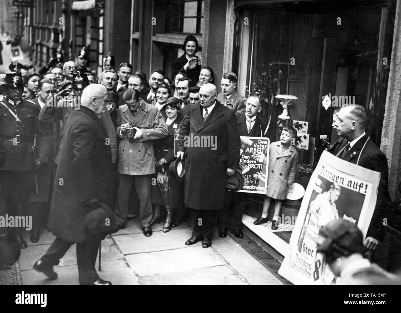 Präsident Paul von Hindenburg und Staatssekretär Otto Meissner auf dem Weg zum Wahllokal anlässlich des Preußischen Landtags Wahlen. Anhänger der einzelnen Parteien stehen mit wahlplakate vor dem Wahllokal. Stockfoto