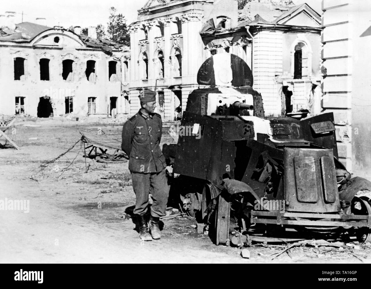 Deutscher Soldat steht vor einem Ausgebrannten sowjetischen Aufklärung Fahrzeug (BA-10) in St. Petersburg. Im Hintergrund, die beschädigten Petershof (ca. 30 km westlich von St. Petersburg). Foto der Propaganda Firma (PK): kriegsberichterstatter Schmidt-Scheeder. Stockfoto