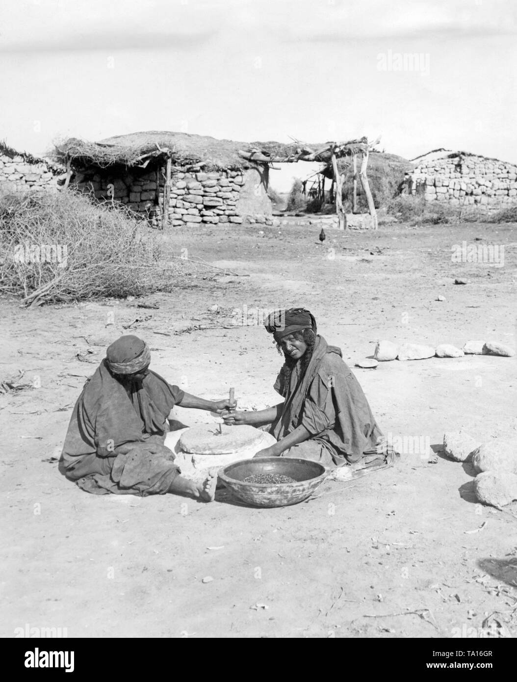 Zwei Bewohner von Jericho im Westjordanland Land mahlen Mais in einem traditionellen Hand Mühle. Stockfoto