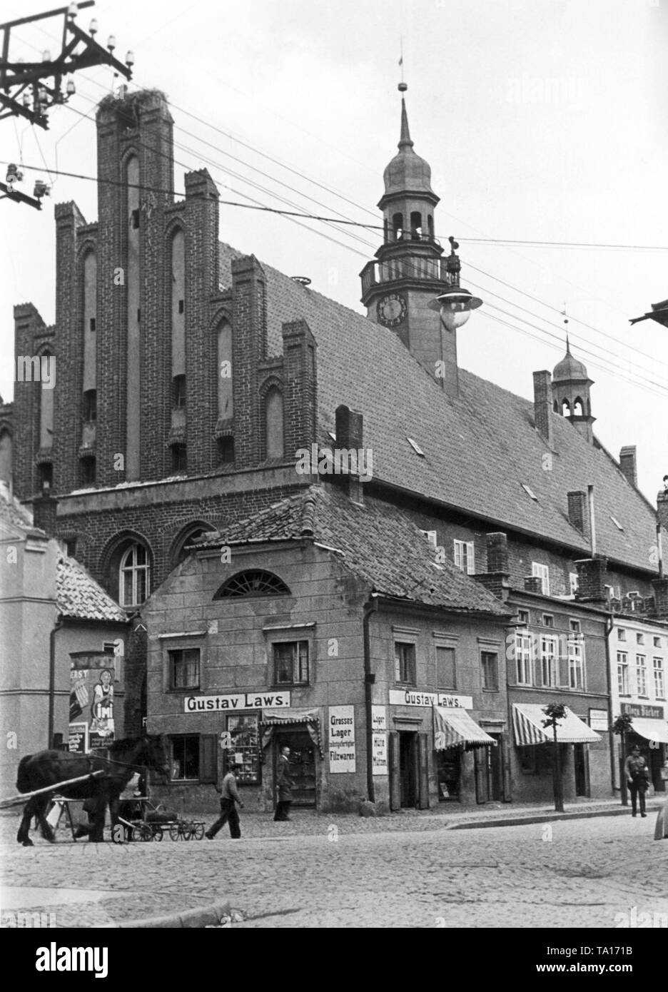 Rathaus in Wormditt (orneta) auf dem Marktplatz in Ostpreußen, vor ihm steht ein Gebäude mit der Aufschrift 'Gustav Gesetze großes Lager selbst - Filz Produkte' gemacht. Stockfoto