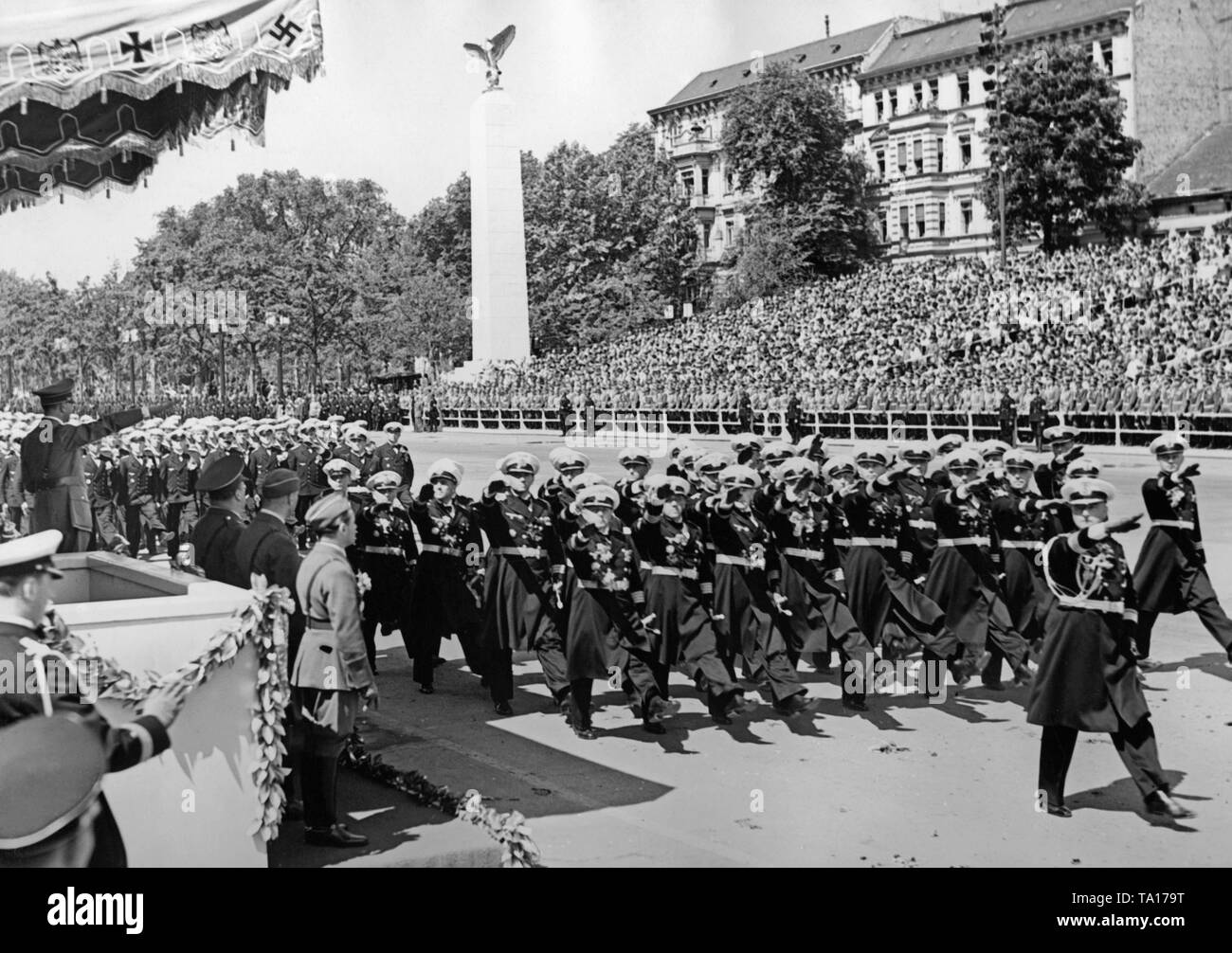 Foto eines marine Formation (die Offiziere geben den Hitlergruss) marschieren vor der Offiziere der Wehrmacht und Führer Adolf Hitler (unter einem Vordach), die auf der Parade der Legion Condor auf der Ost-West-Achse (ehemalige des Chalottenburger Chaussee, heute Straße des 17. Juni) vor der Technischen Universität am 6. Juni 1939. Stockfoto