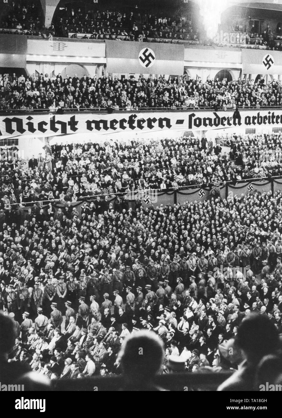 Der Slogan "Nicht meckern, sondern arbeiten!' ('Do Nicht nag, aber arbeiten!') bezieht sich auf die Kritiker des NS-Regimes, die hartnäckige Genörgel beschuldigt wurden. Hier auf ein Banner in einer Nsdap Ereignis im Sportpalast Berlin im Herbst 1933. Stockfoto