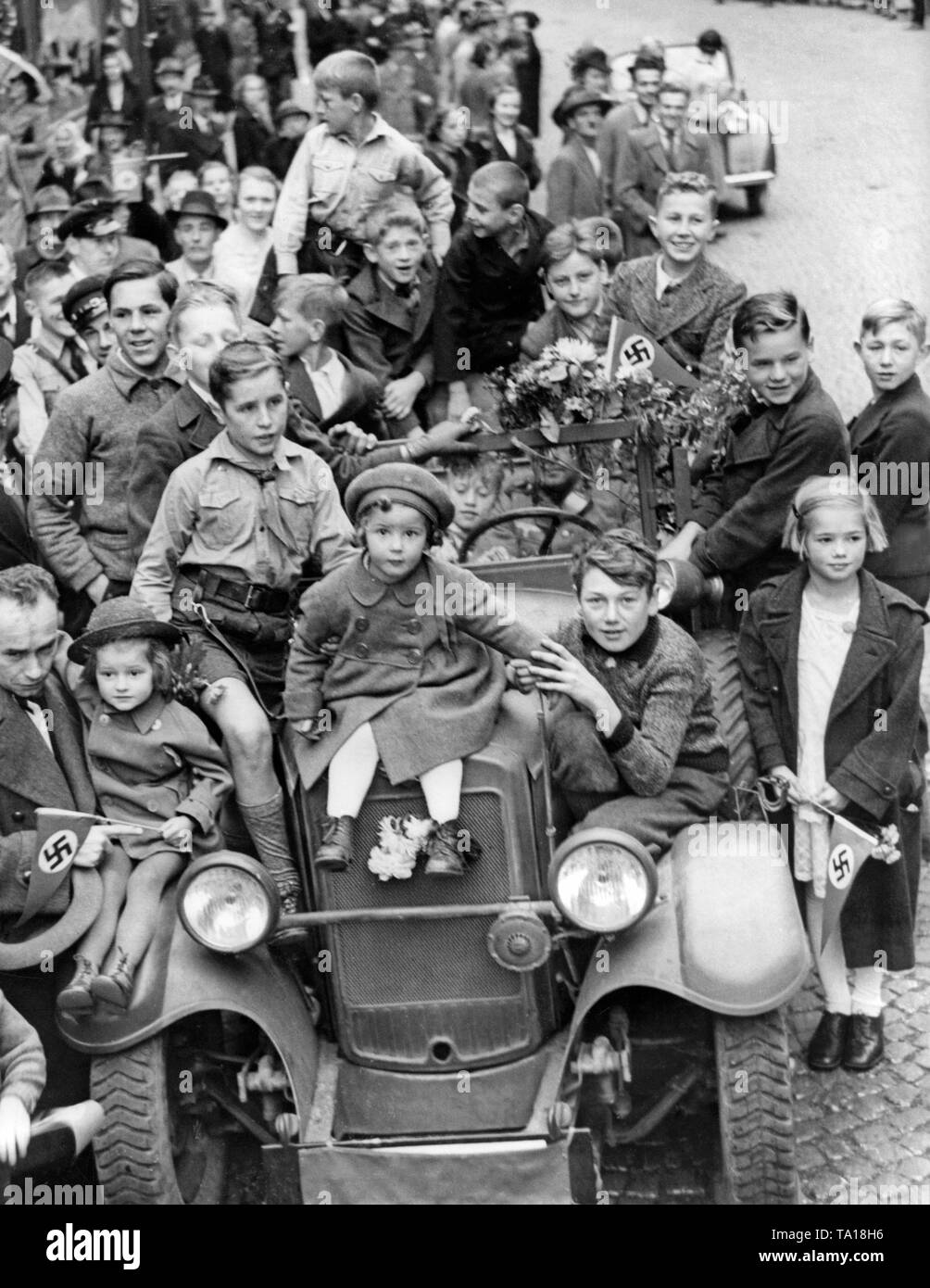 Eine Gruppe von Kindern steht oder sitzt auf einem Fahrzeug der Wehrmacht am 4. Oktober 1938, heute in Karlsbad (Karlovy Vary) während der Besetzung des Sudetenlandes durch deutsche Truppen. Stockfoto