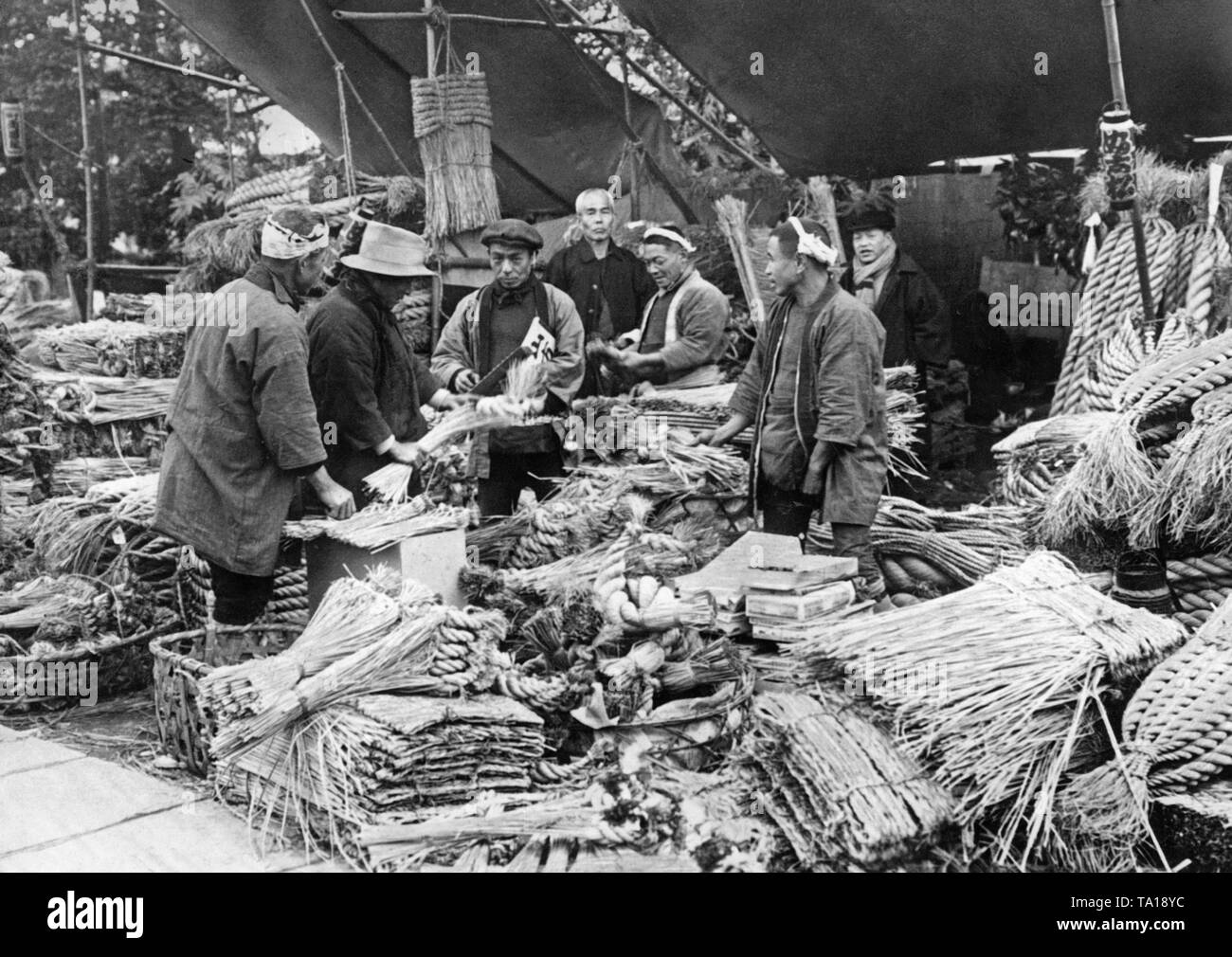 Am 18. Dezember 1935 im Rahmen der Vorbereitungen für die Japanische Neujahrsfest, einige Männer kaufen Glücksbringer auf einem Markt, der an der vorderen Tür angebracht sind. Stockfoto