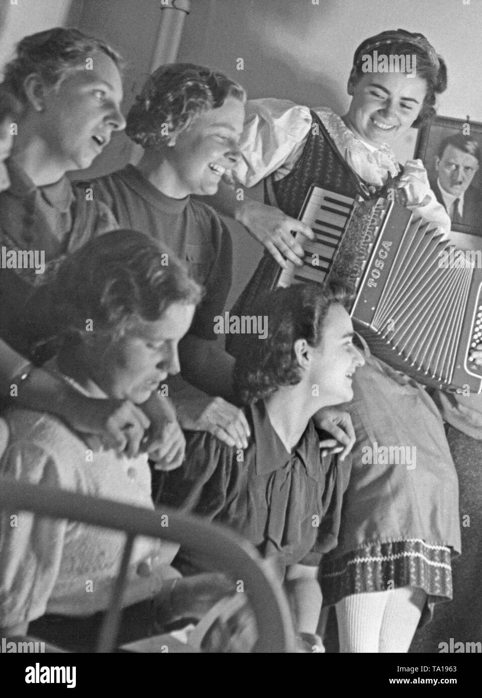 Schüler singen im 'Vielmaederlhaus' in Wien. An der Wand ein Porträt von Adolf Hitler. Stockfoto