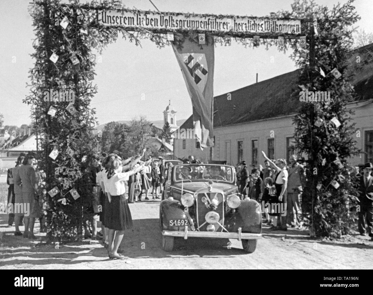 Slowakische Staatssekretär Franz Karmasin fahren durch einen deutschsprachigen Slowakischen Dorf. Die Bewohner geben ihm den Hitlergruß. Das Banner liest (englische Übersetzung): "Herzlich Willkommen auf unserer Liebe Community Leader". Stockfoto