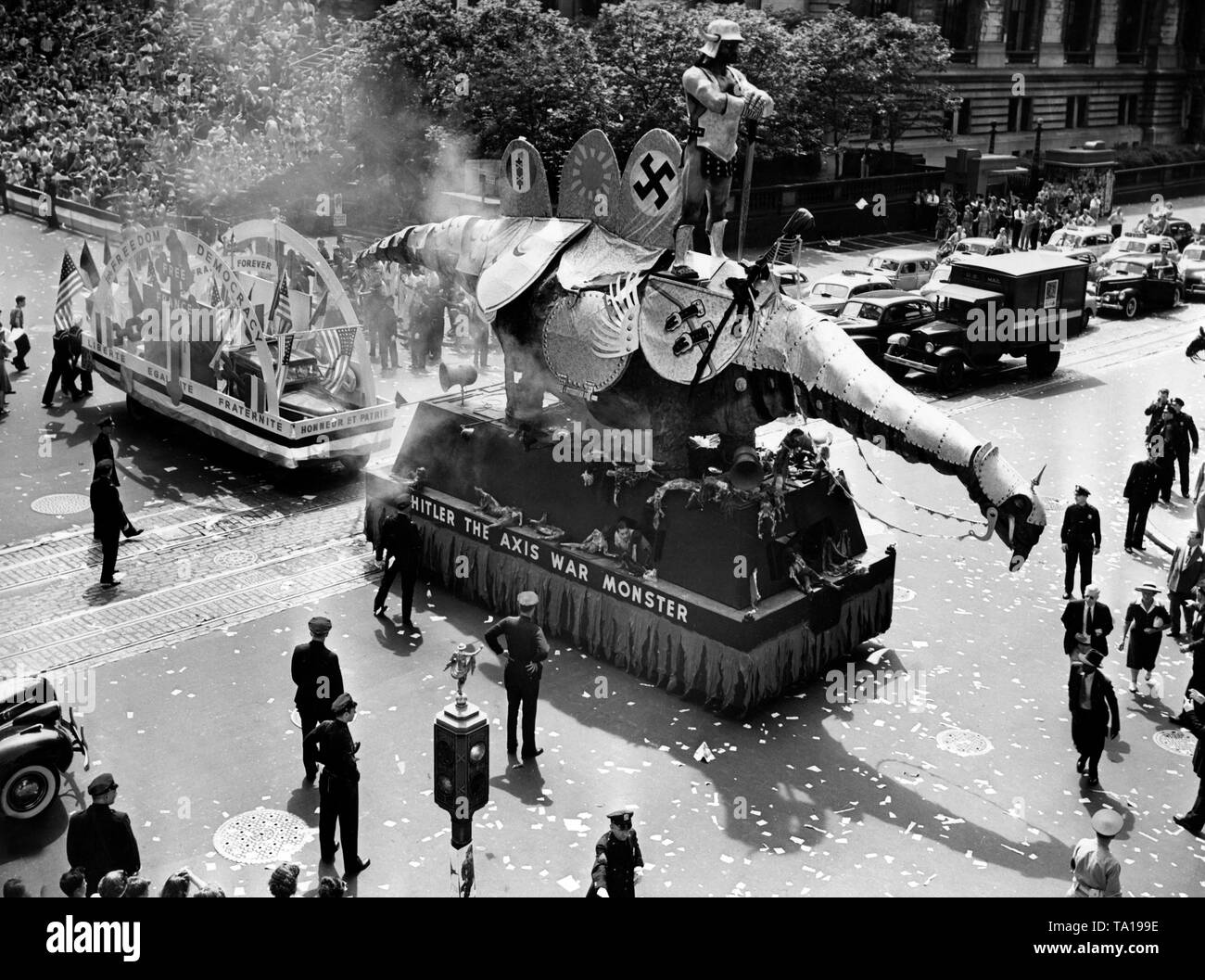 Eine Prozession in New York führt ein Auto, an dem Hitler sitzt als menschenfressende Monster mit den Worten "Hitler die Achse Krieg Monster'. Hinter, ein Auto, das war für das freie Frankreich zu stehen. Auf dem Auto die Inschriften "Liberté, Egalité, Fraternité, Honneur et Patrie" und "Freiheit, Demokratie, freien Frankreich Forever'. Neben das Hakenkreuz, das Symbol von Japan (die Sonne) und die Fasces für das faschistische Italien stehen. Stockfoto