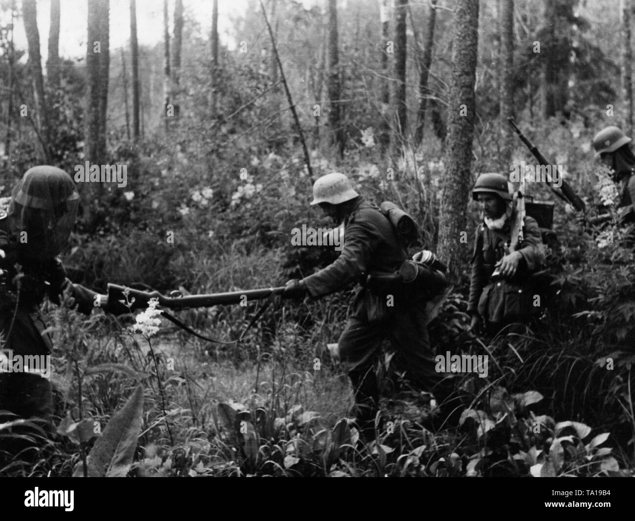 Deutsche Infanterie kreuzt ein Sumpfgebiet östlich von Kowel. Der Soldat auf der linken Seite trägt ein Moskitonetz über seinen Helm. Stockfoto