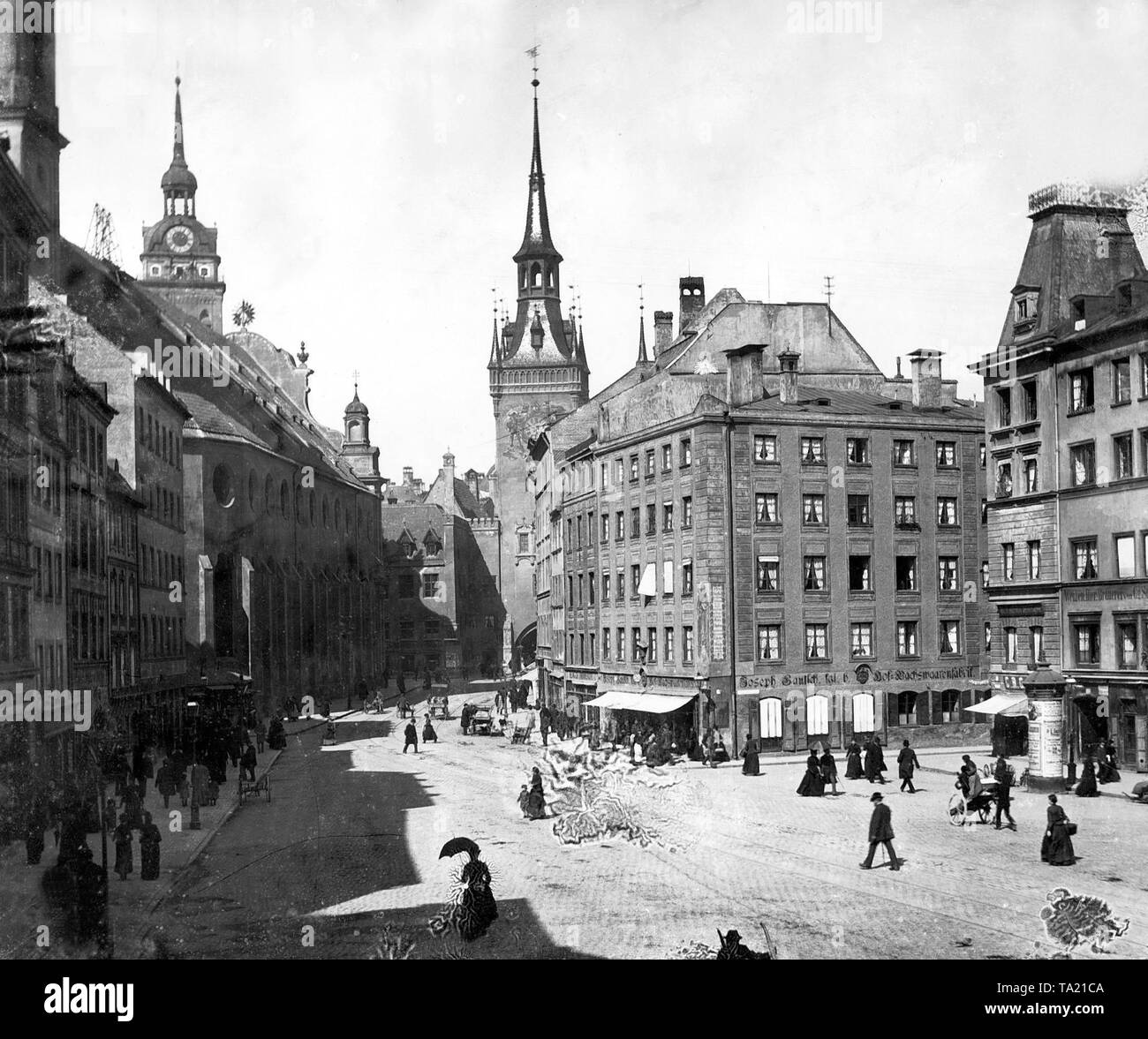 Straße im Zentrum von München um 1900. Im Hintergrund der Turm des Alten Rathauses. Die Kirche des Heiligen Geistes und den Turm von St. Peter. Stockfoto