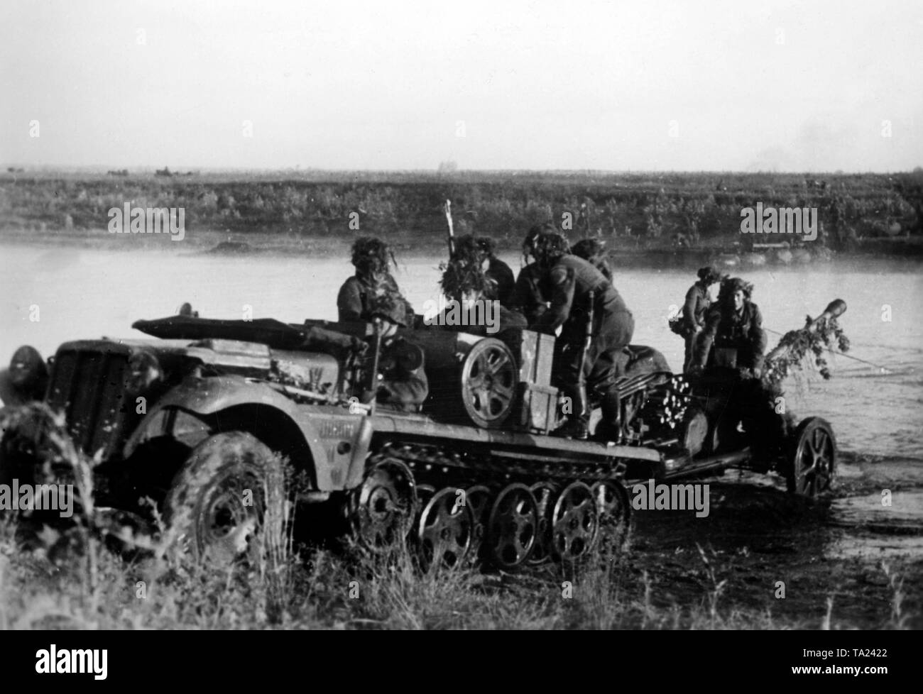 Deutsche Infanteristen Kreuz ein kleiner Fluss im südlichen Abschnitt der Ostfront in der Nähe von Schtschigry mit einem leichten Zugkraftwagen 1t (SdKfz. 10) und eine gezogene Pak 5 cm 38. Die Helme der Soldaten und die Waffe mit Zweigen getarnt sind. kriegsberichterstatter: Kirchner. Stockfoto