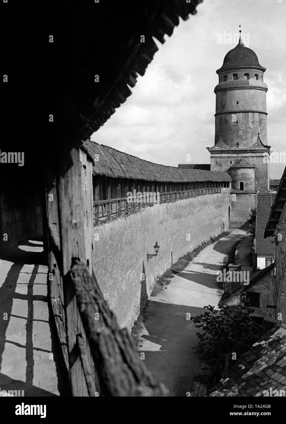Zinne der erhaltenen Stadtmauer von Nördlingen. Im Hintergrund die Loepsinger oder Deininger Tor. Stockfoto