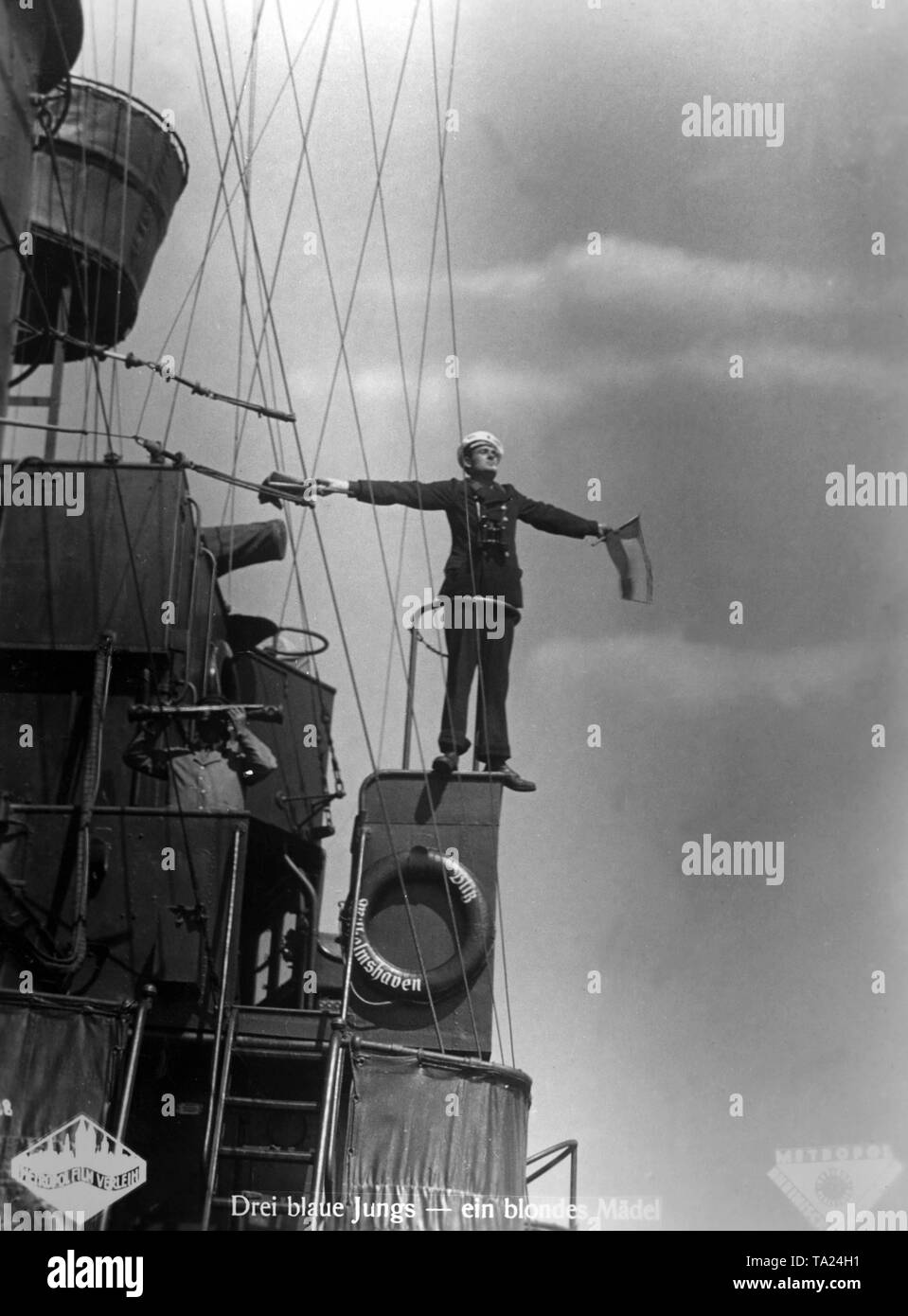 Moviestill aus "Drei Bluejackets und eine Blonde" von 1933, in dem Heinz Ruehmann eine führende Rolle gespielt. Das Bild zeigt die Schauspieler Friedrich Benfer als Seemann, der flaggensignale an Bord des Fernleitschiff 'Blitz' gibt. Stockfoto