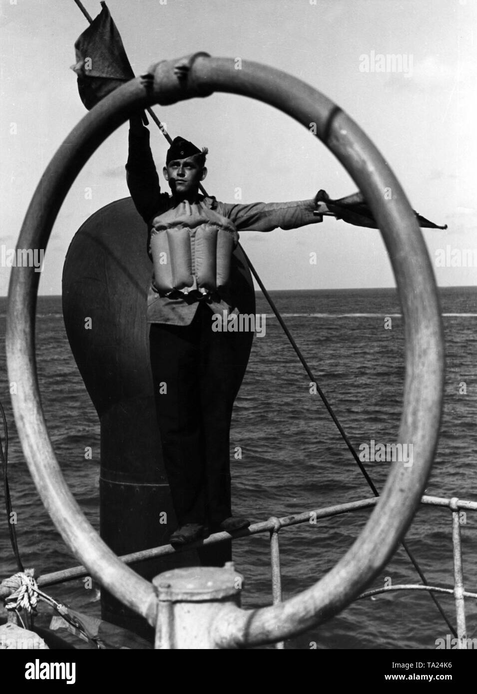 Ein Rekrut der Kriegsmarine Signalisierung an Bord eines deutschen Schiffes, er trägt eine Rettung Weste. Stockfoto