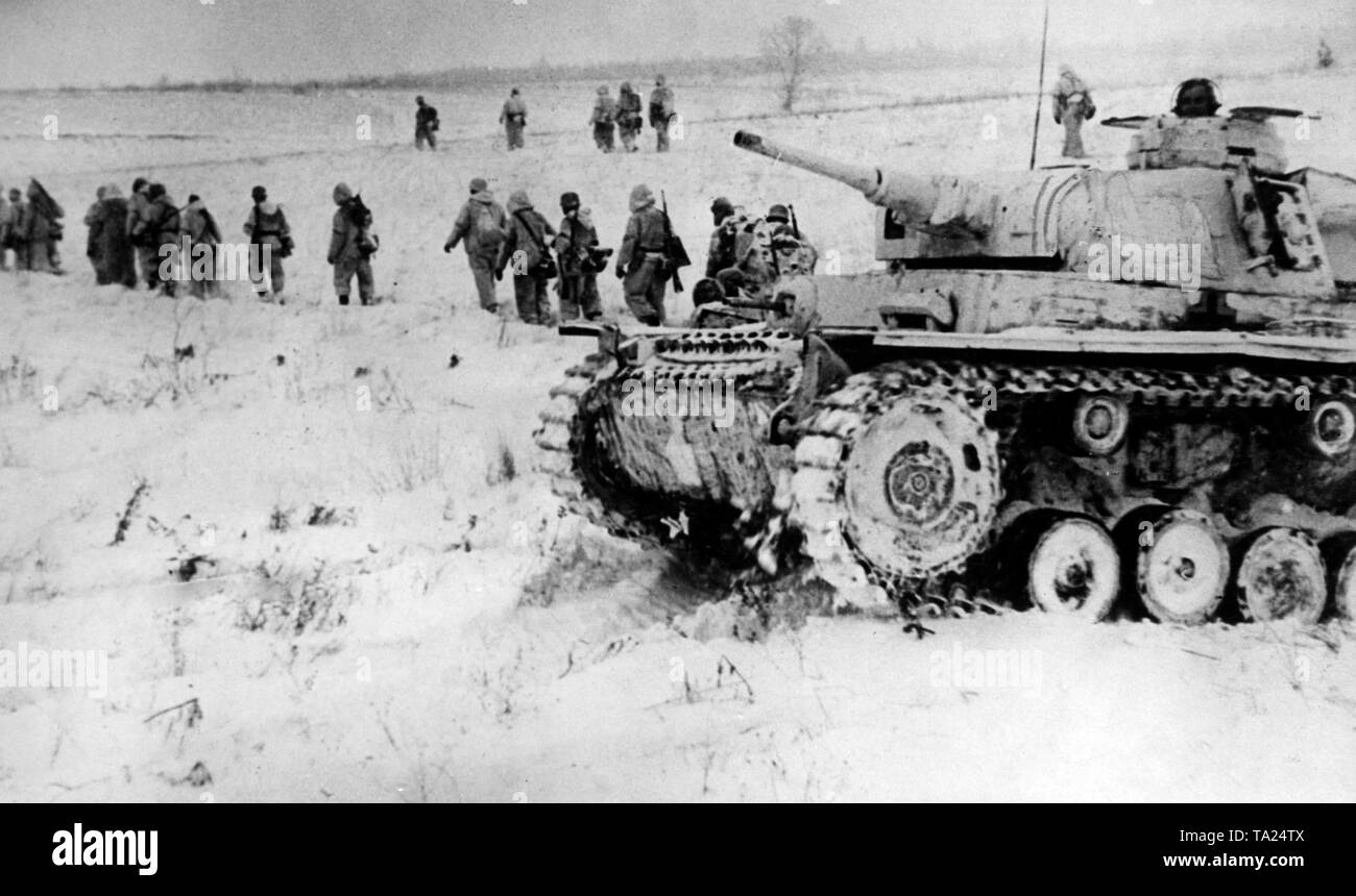 Deutsche Soldaten der SS marschieren über einem schneebedeckten Feld in der Nähe von Toropez, auf der rechten Seite, ein PANZERKAMPFWAGEN III. (Foto von der Propaganda Firma (PK)/SS). Stockfoto