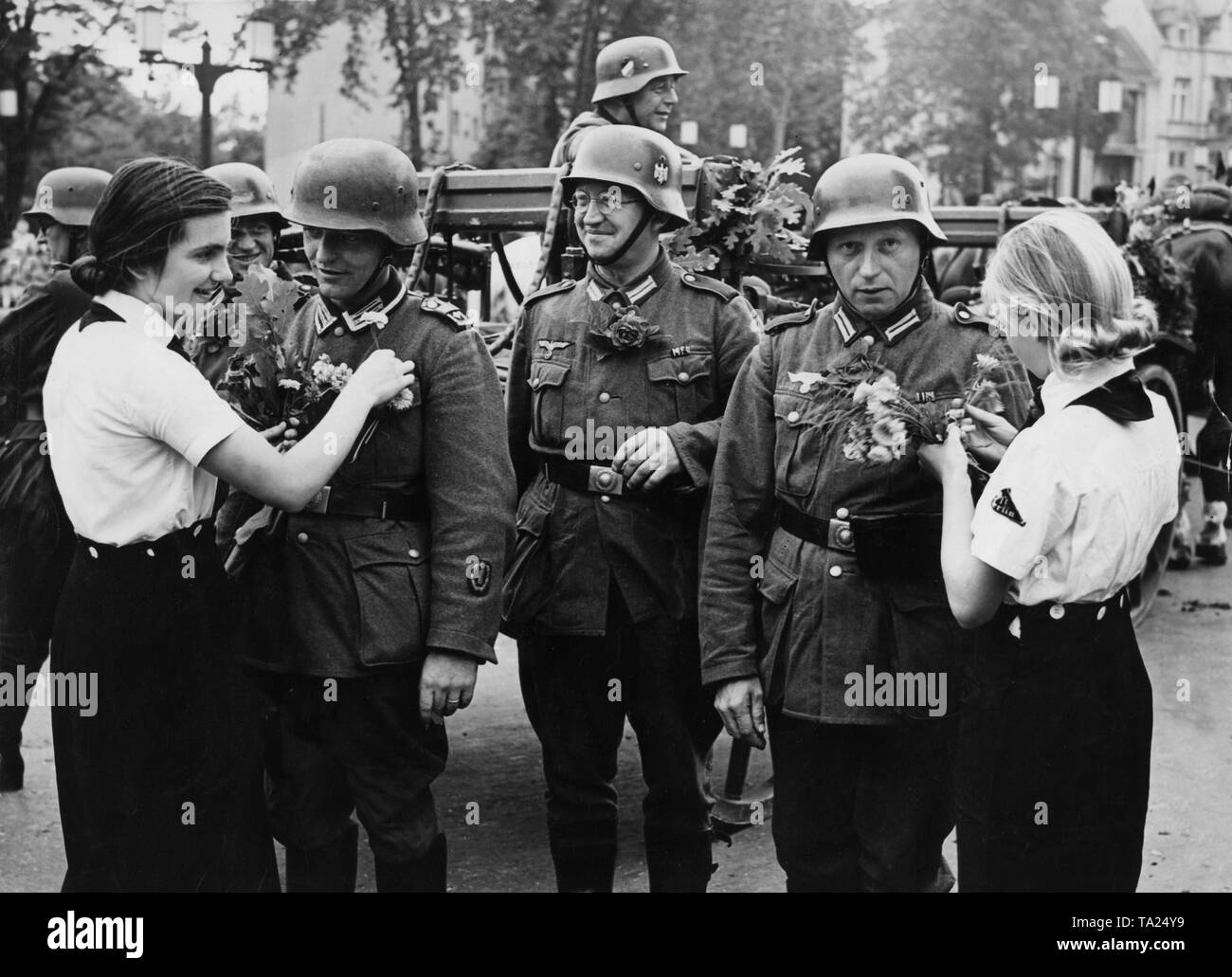 BDM-Mädchen sind Soldaten mit Blumen verziert, der an die Ost-West-Achse für einen März gesäumt. Stockfoto