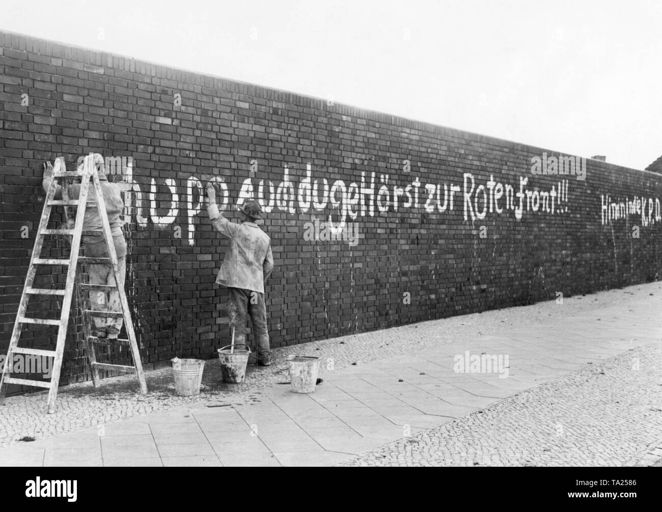 Zwei Männer waschen aus einem kommunistischen Inschrift aus einer Fabrik Wand in Lichtenberg. Der Slogan appelliert an die Mitglieder der Wasserschutzpolizei: Chupo, gehören Sie zu den roten Front sowie!!!" Stockfoto