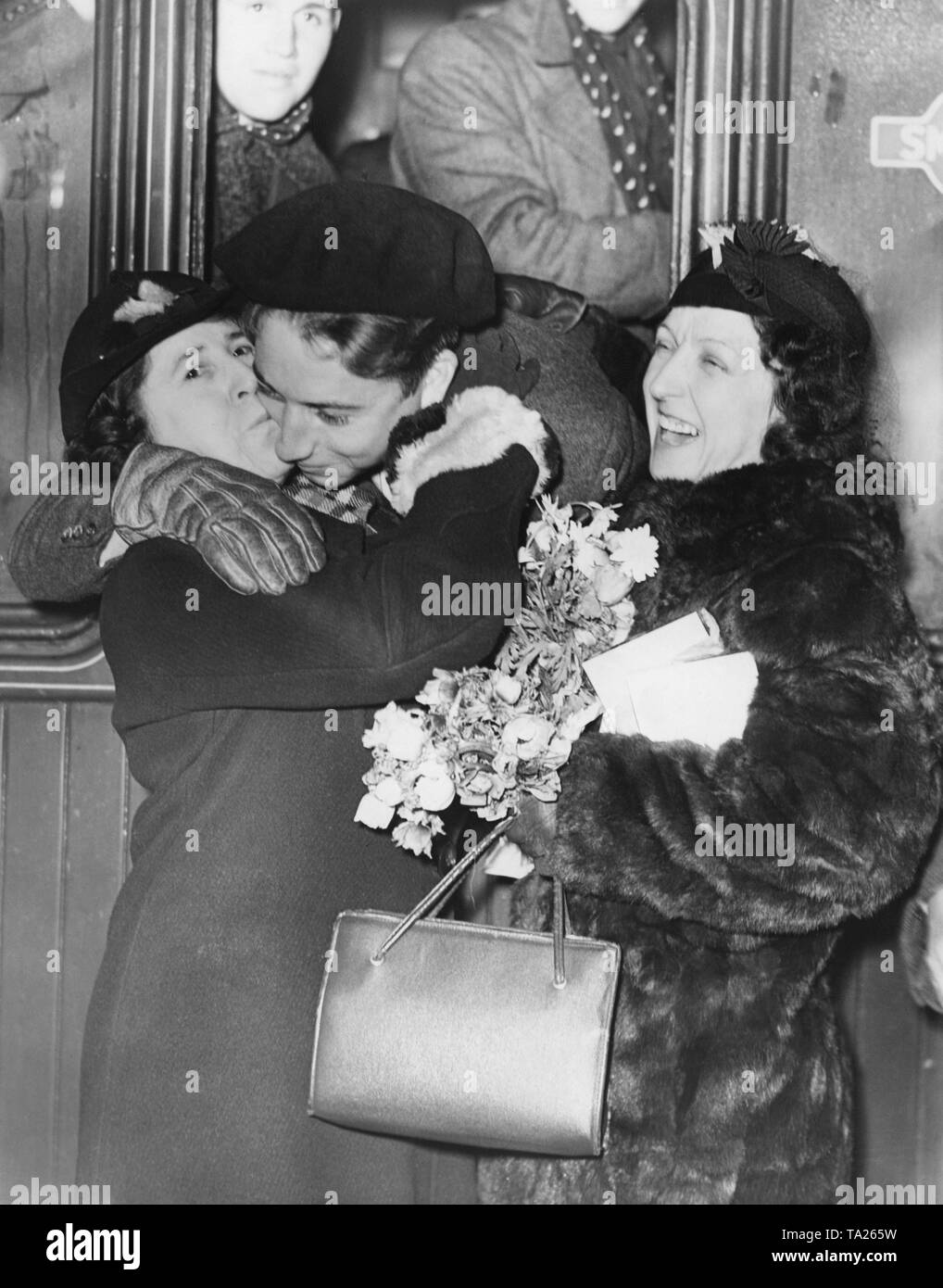 Foto eines freiwilligen Republikanischen Kämpfer des Bürgerkrieges, der von zwei Frauen an der Victoria Station in London nach ihrer Rückkehr aus dem Spanischen Bürgerkrieg am 7 Dezember, 1938 geküsst wird. Die 400 Kämpfer der Internationalen Brigaden am Bahnhof von einer Menschenmenge und sozialistischen Beamten erhalten. Stockfoto