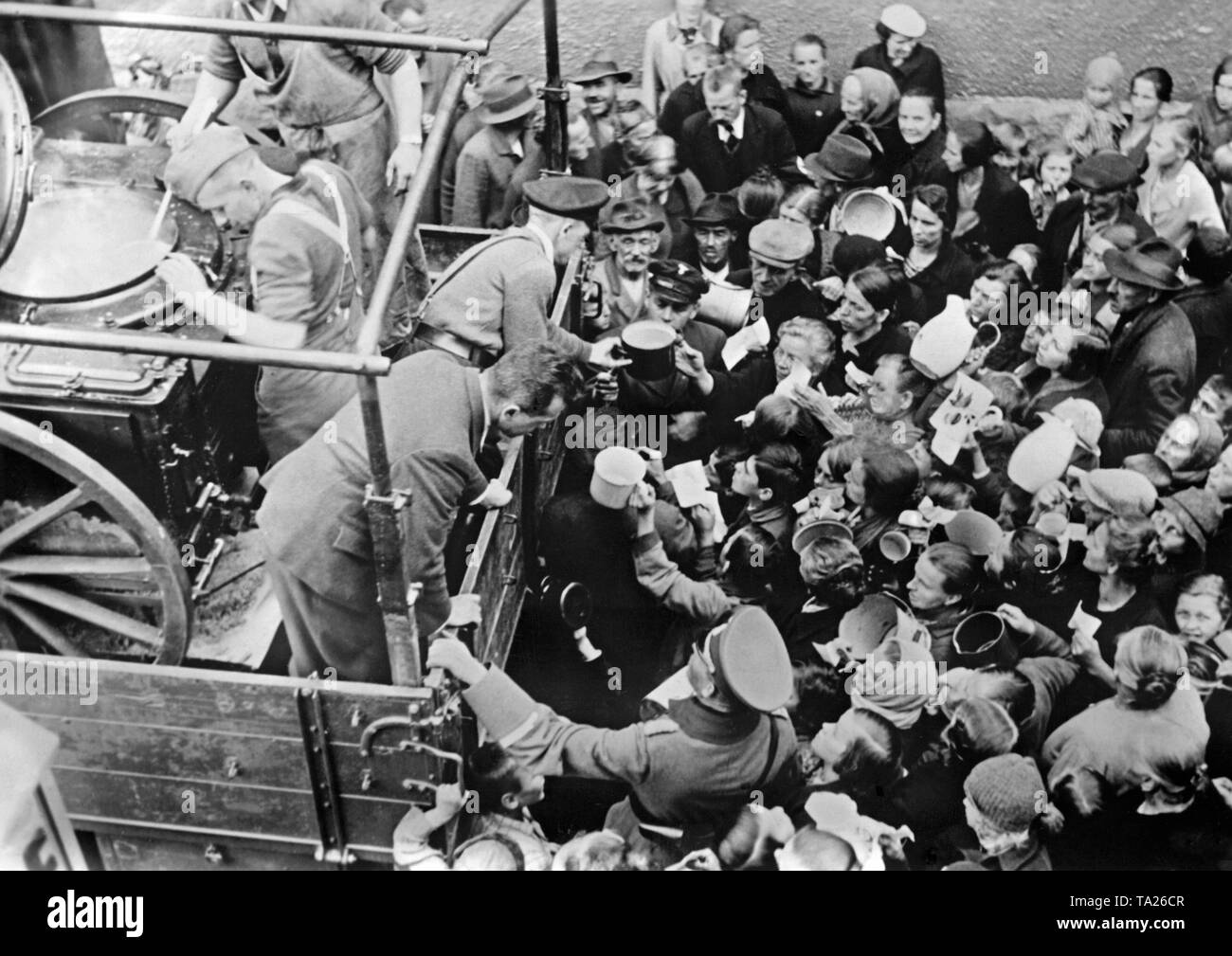 Deutsche Soldaten Suppe in die am 14. Oktober 1938 zu verteilen, als Teil der ungelernten Arbeitskräften der Nationalsozialistischen für das Wohl der Menschen. Eine Traube von Menschen hat sich um den Truck gebildet. Sie mit der Hand über die Töpfe und andere Behälter für die Soldaten. Stockfoto