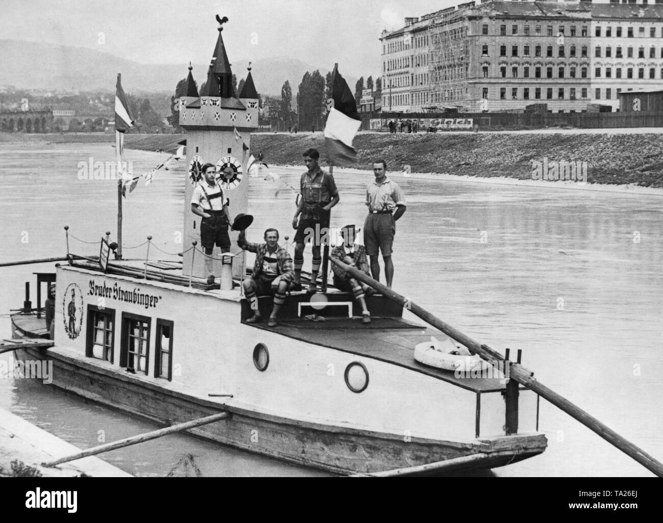 Sechs Arbeitslose aus dem bayerischen Straubing, Bootfahren auf der Donau auf ihren selbst gebauten Boot. Das Schiff ist mit einer Nachbildung der Straubing City Tower sowie die Österreichische und Deutsche Fahnen dekoriert. Hier sind Sie an der Friedensbrueck in Wien. Stockfoto