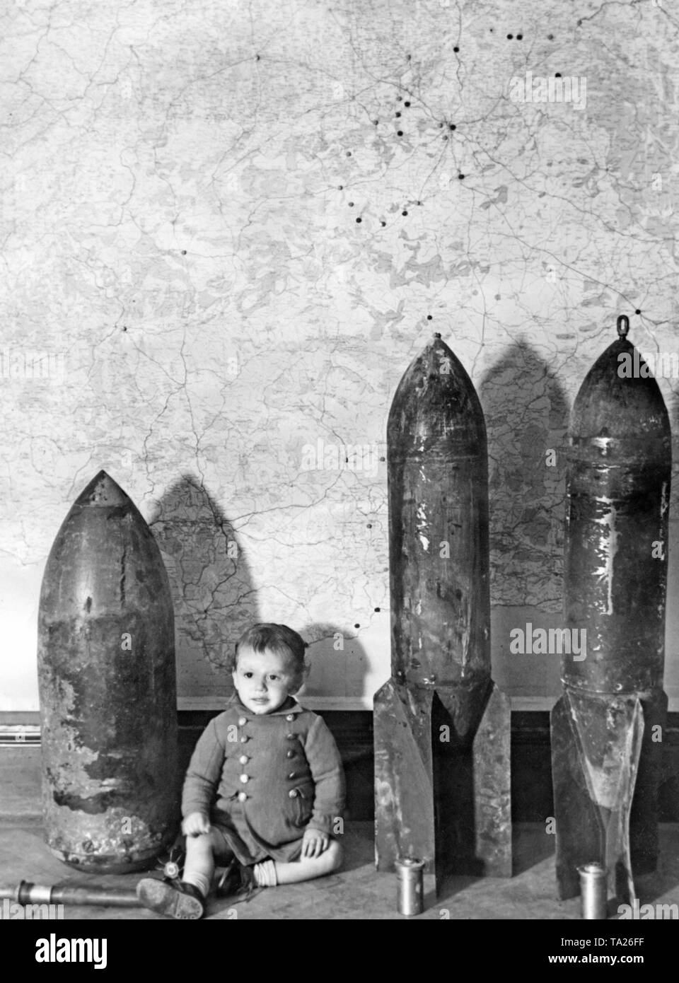 Foto von deutschen oder italienischen Klamotten in Madrid im Jahr 1937. Ein Kleinkind war neben der Antenne Bomben gelegt. Im Hintergrund, eine Karte von Spanien mit der Hauptstadt Madrid, wo die Bombardierungen des Nationalen Spanischen Truppen angezeigt werden. Vor den Bomben, die detonatoren. Stockfoto