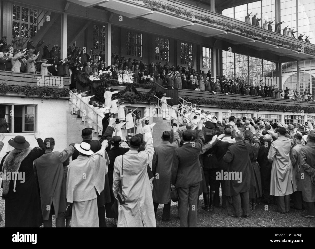 Besucher der Rennbahn Riem zeigen den Hitlergruß bei der Eröffnung einer neuen Tribüne. Stockfoto