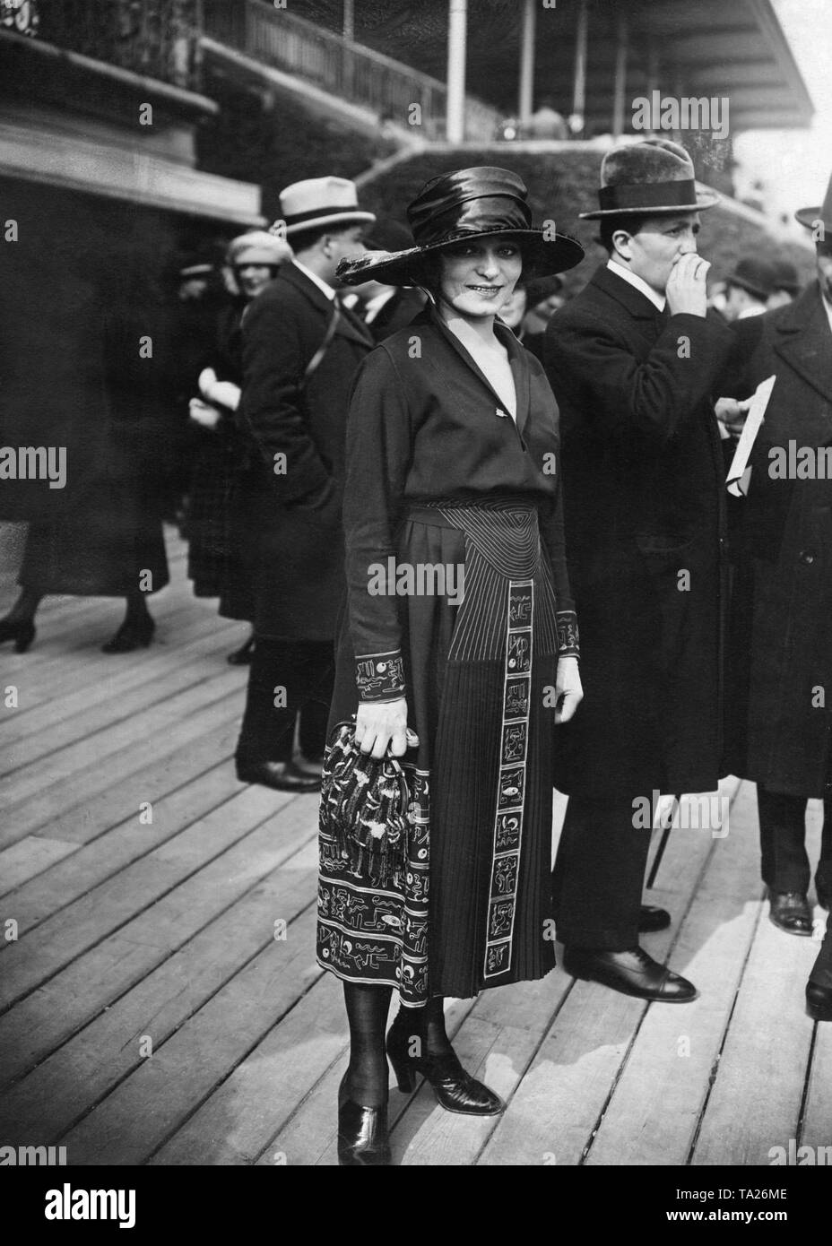 Eine Dame in einem dunklen Kleid mit zweifarbigen Kairo Stickerei und Hut. Stockfoto