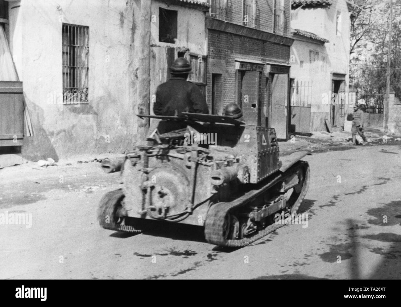 Foto von der Rückseite eines italienischen 2-Mann Tank (L3/33, Carro Veloce 33) des Corpo Truppe Volontarie (CTV), durch die Mitte von Villaverde del Rio, nördlich von Sevilla. Die Besatzung trägt Leder Helme. Stockfoto